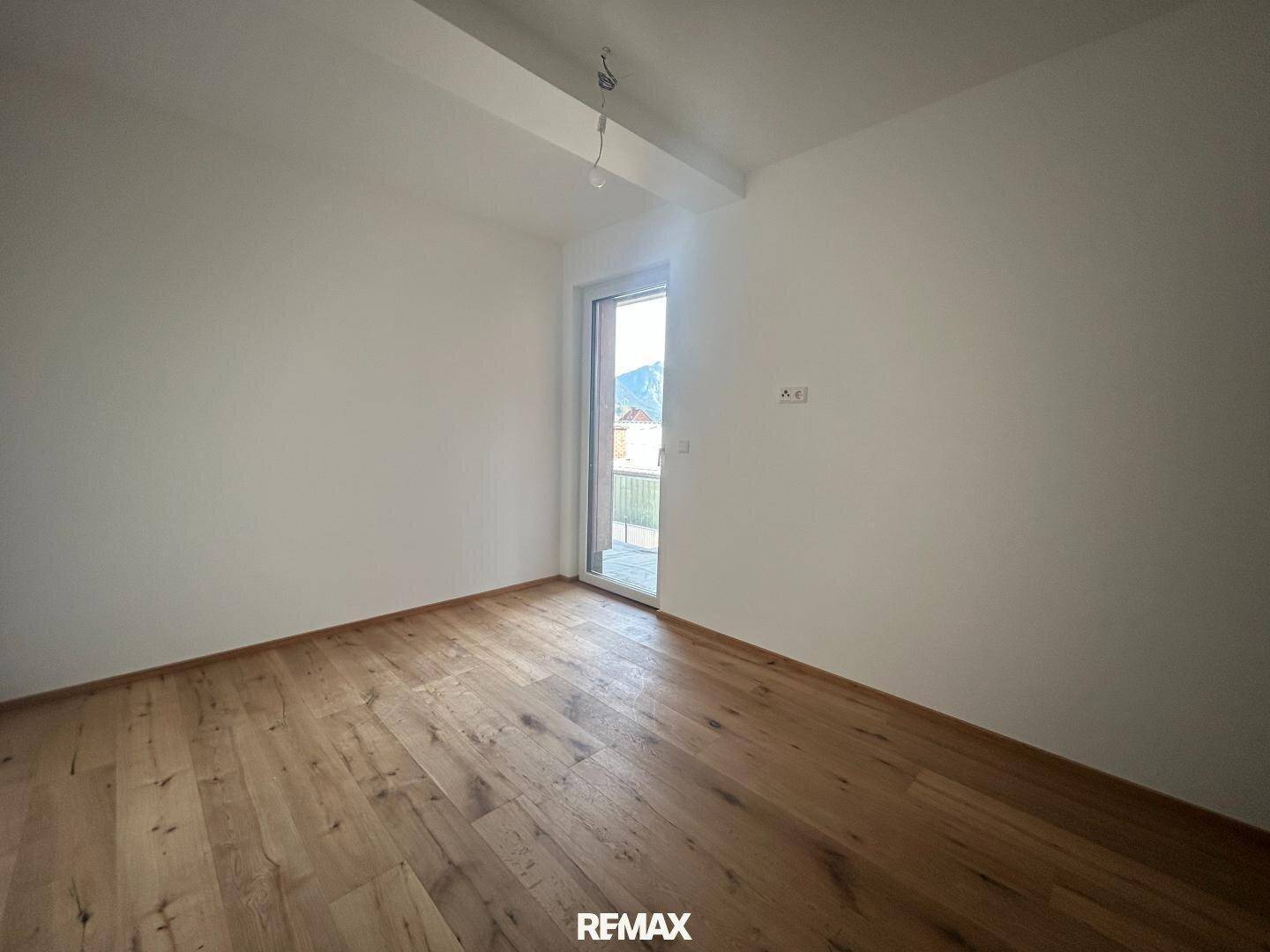 Helles Zimmer mit Parkettboden und Zugang zu einem potenziellen Außenbereich.