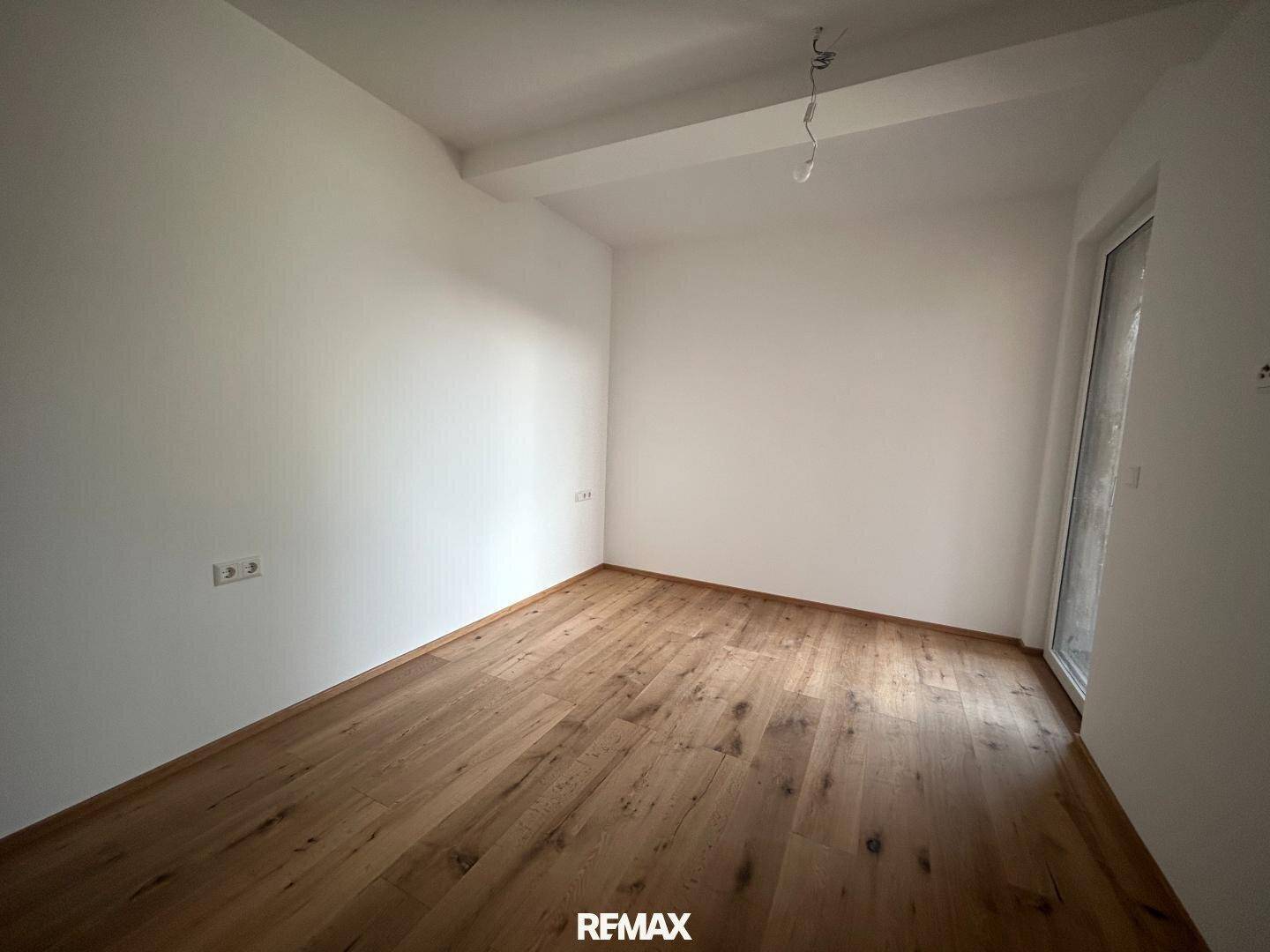 Helles Zimmer mit Holzboden und weiß gestrichenen Wänden, ideal als Schlafzimmer.