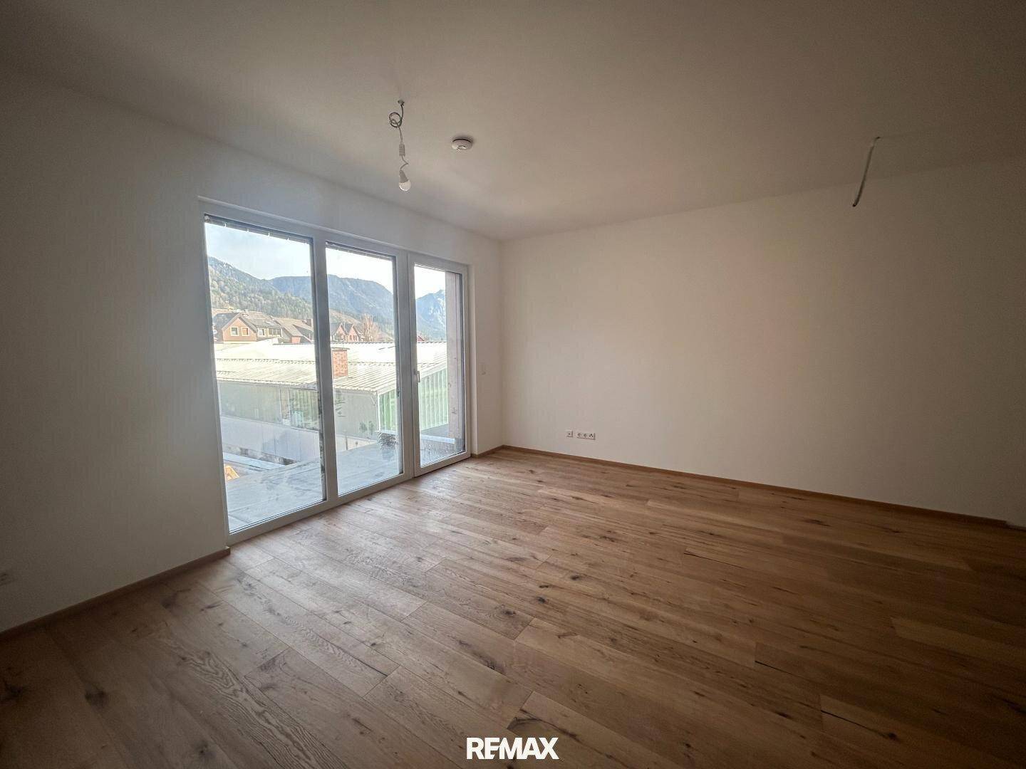 Geräumiges Zimmer mit hellem Parkettboden und bodentiefen Fenstern für viel Tageslicht.