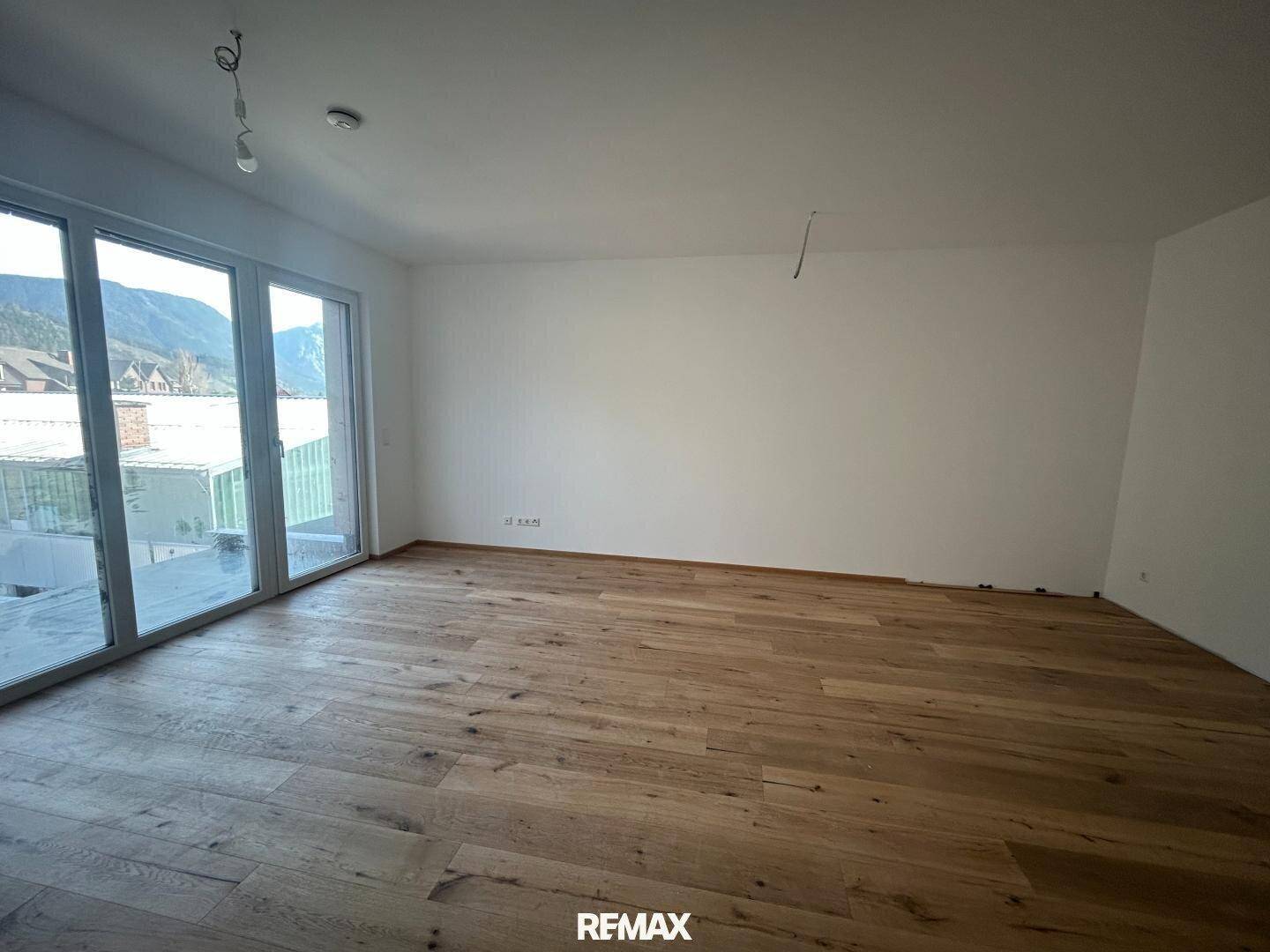 Helles Zimmer mit neuem Eichenparkettboden und großen Fenstern mit Bergblick.