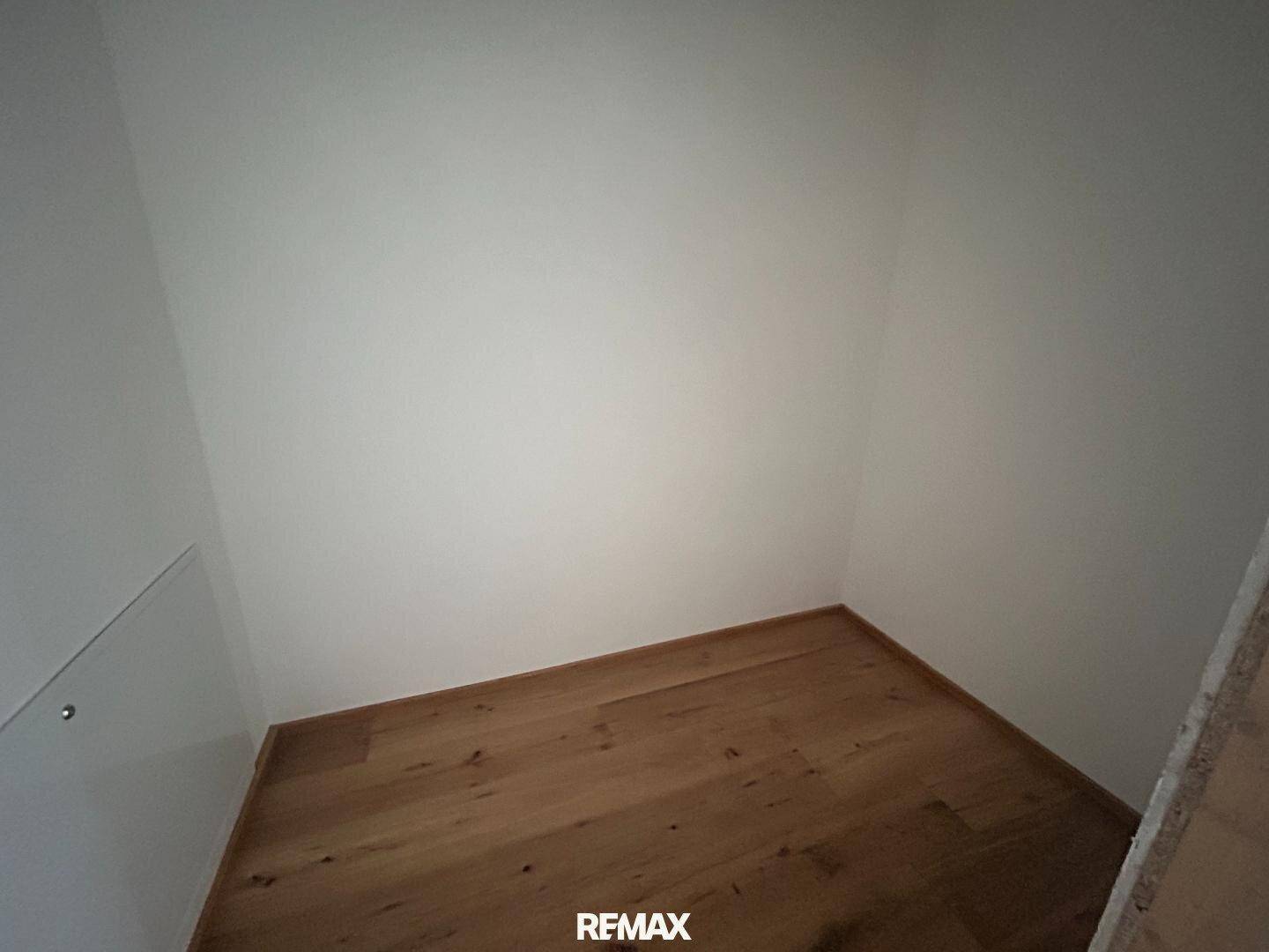 Kleiner Abstellraum mit weißen Wänden und Holzboden, ideal für zusätzlichen Stauraum.
