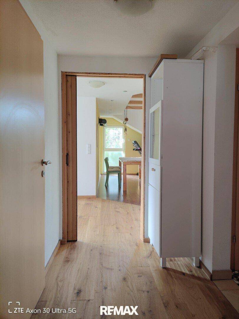 Heller Flur mit Holzboden, der zu einem Essbereich mit Tisch führt.