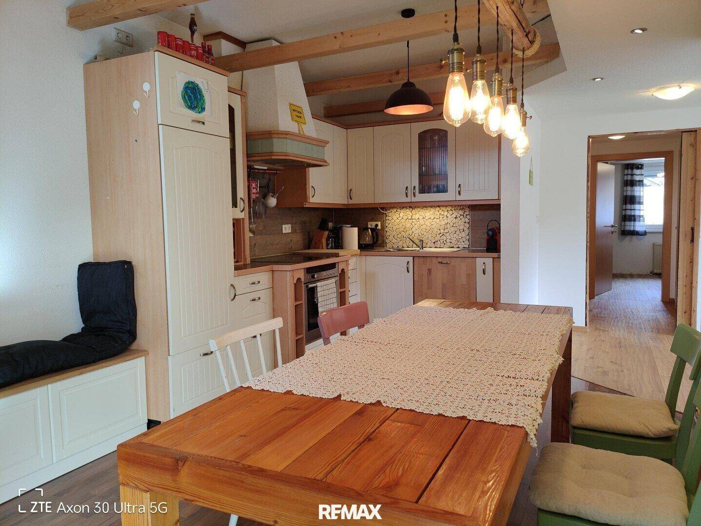 Rustikale Küche mit Essbereich, Holztisch, Holzschränken und sichtbaren Deckenbalken.