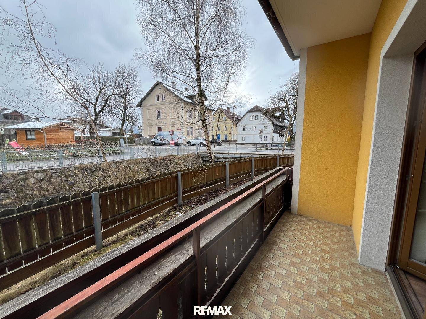 Balkon mit Blick auf die Straße und umliegende Gebäude, ausgestattet mit einem Geländer und einer Rampe.