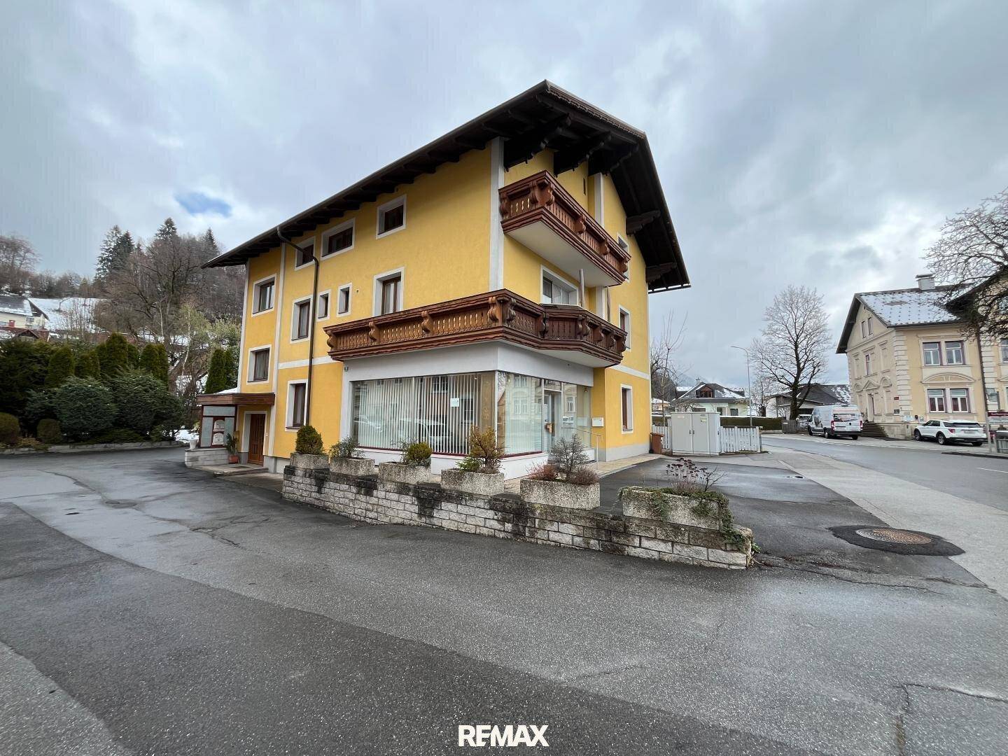 Seitenansicht des gelben Gebäudes mit traditionellen Holzbalkonen und umliegender Straße.
