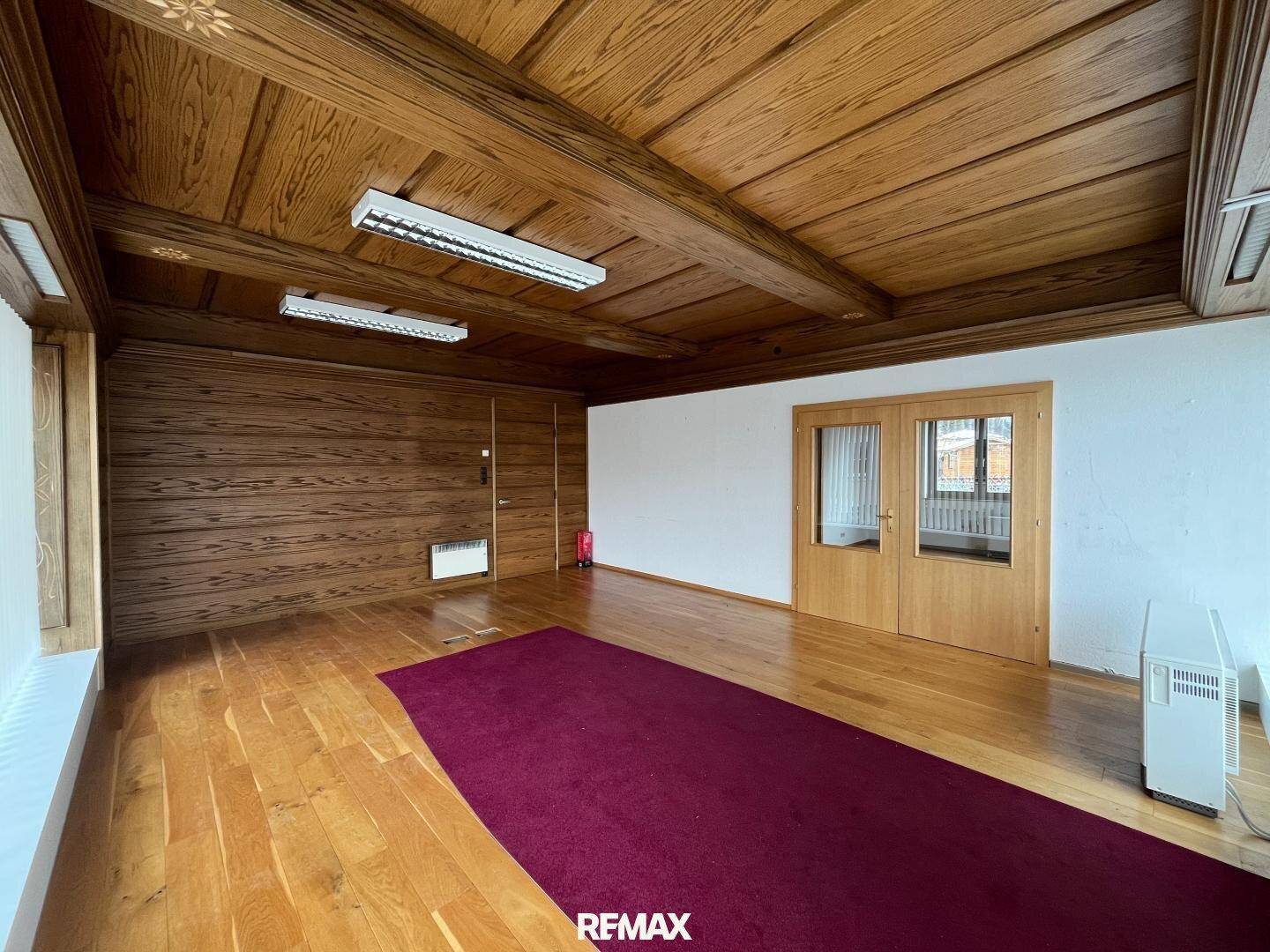 Geräumiger Innenraum mit Holzböden, Holzdecken und einer roten Teppichläufer, der eine warme Atmosphäre schafft.