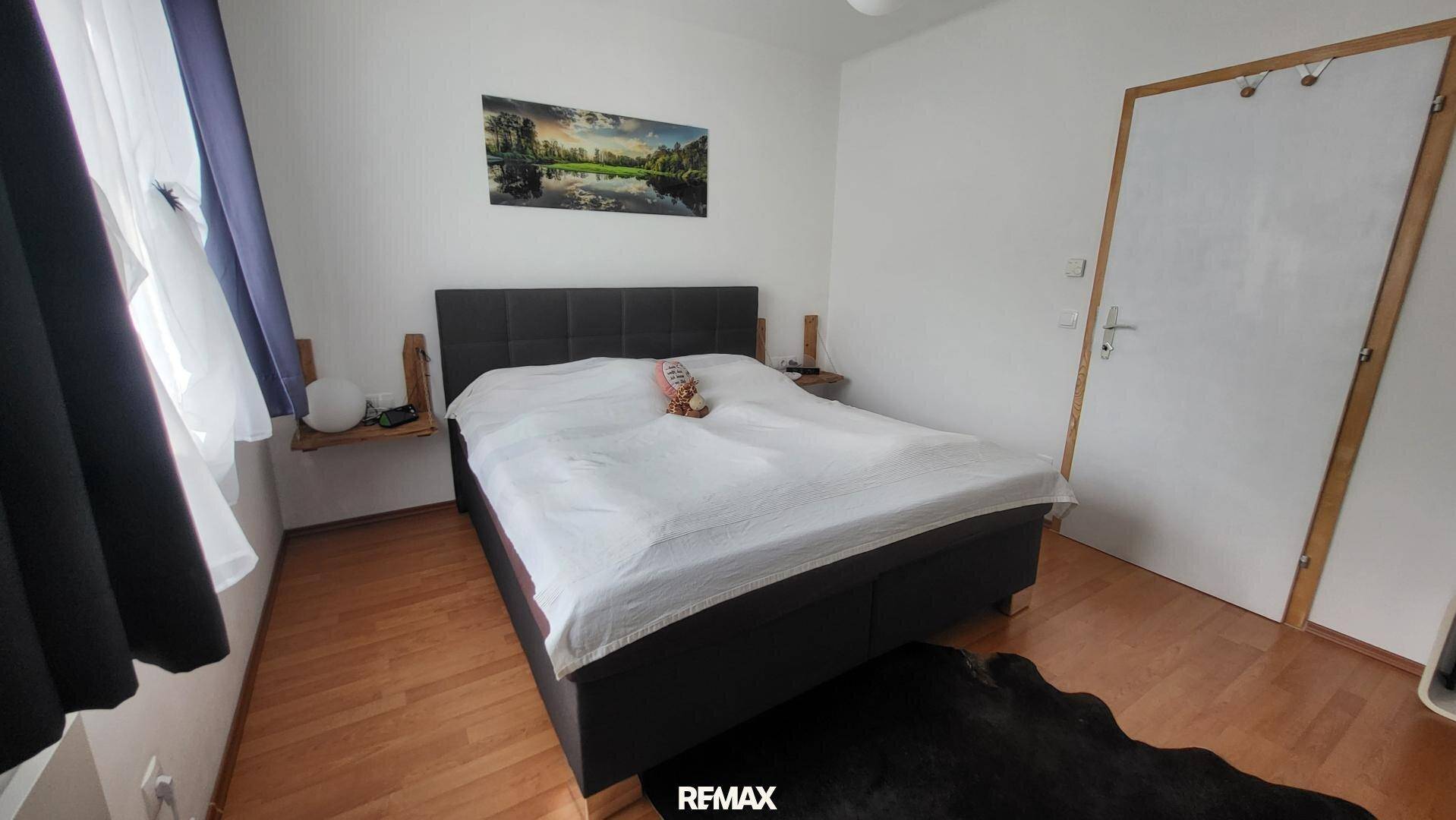 Gemütliches Schlafzimmer mit Doppelbett, Holzfußboden und Fenster, bietet eine ruhige Atmosphäre.