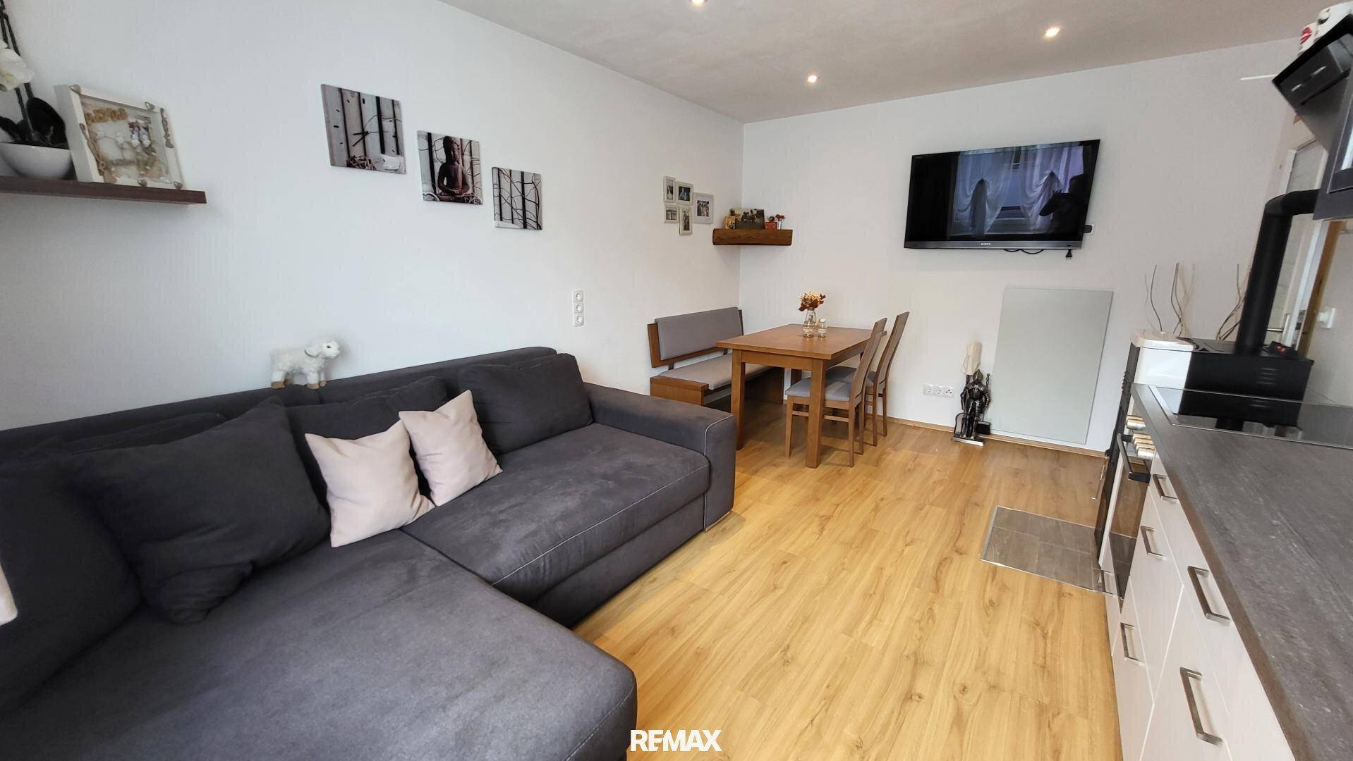 Offener Wohn- und Essbereich mit Sofa, Esstisch und Wandfernseher, ideal für geselliges Beisammensein.