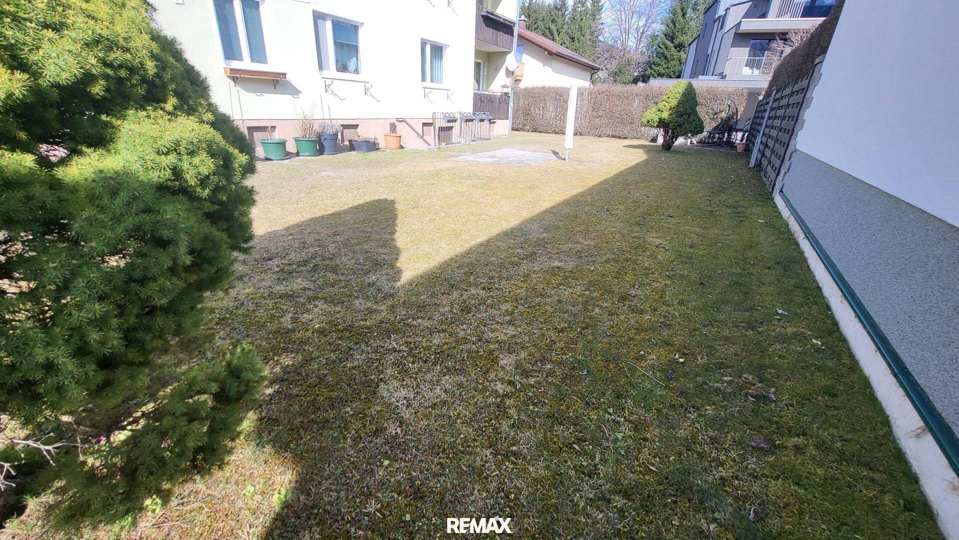 Gepflegte Rasenfläche im Gartenbereich des Anwesens mit Sträuchern und Zaun.
