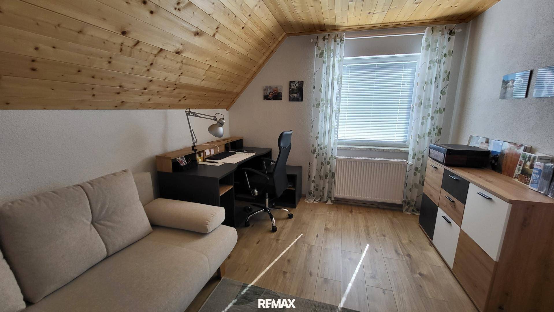 Heller Arbeitsbereich im Dachgeschoss mit Holzdecke, Schreibtisch und praktischen Möbeln.