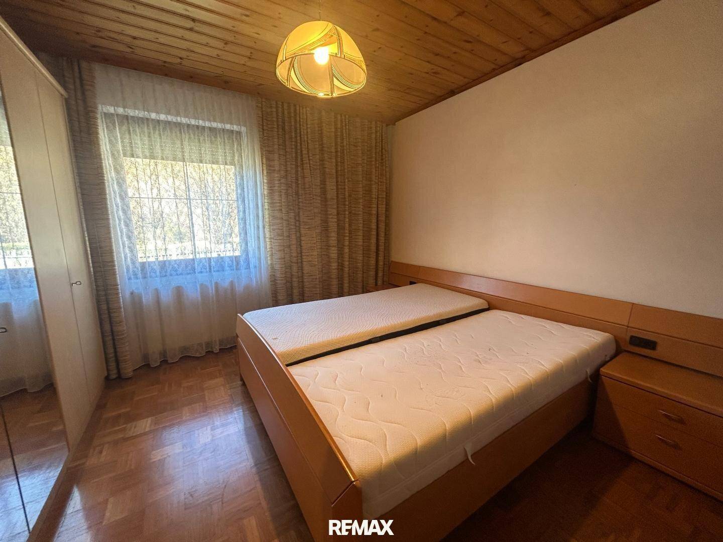 Gemütliches Schlafzimmer mit Holzbalkendecke, Parkettboden und einem großen Doppelbett.