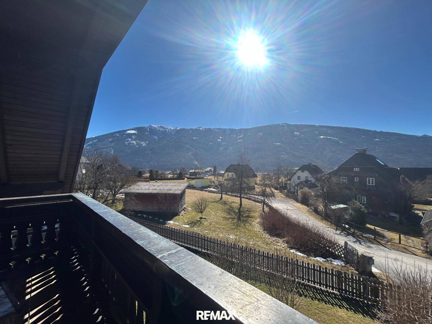 Sonniger Balkon mit Holzbalkonbrüstung und weitem Blick auf die Berge und die umliegende Landschaft.