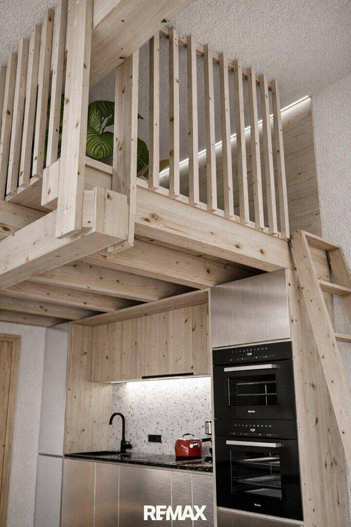Detailansicht der modernen Küche mit Edelstahlfronten unter dem Holz-Loft.