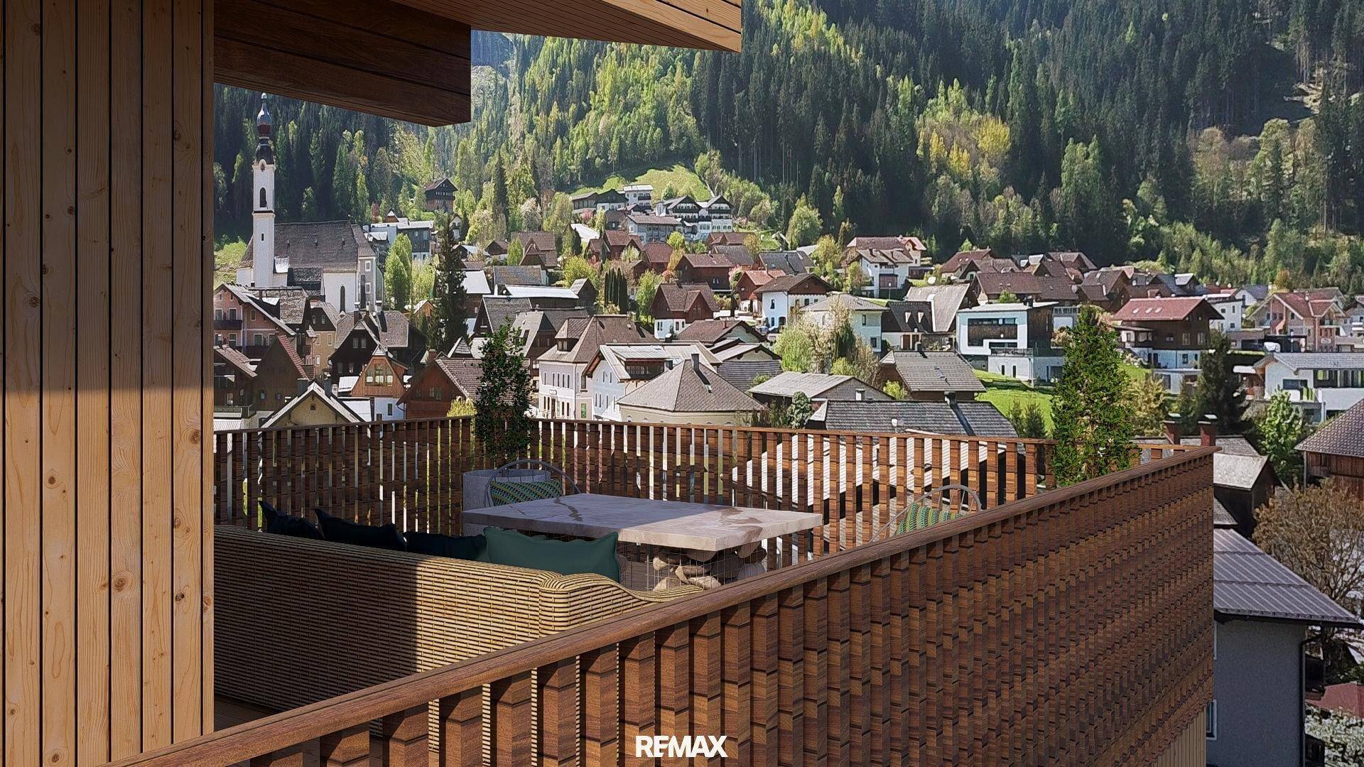 Geräumige Holzterrasse mit Sitzgelegenheiten und einem malerischen Blick auf das Dorf und die umliegenden Berge.
