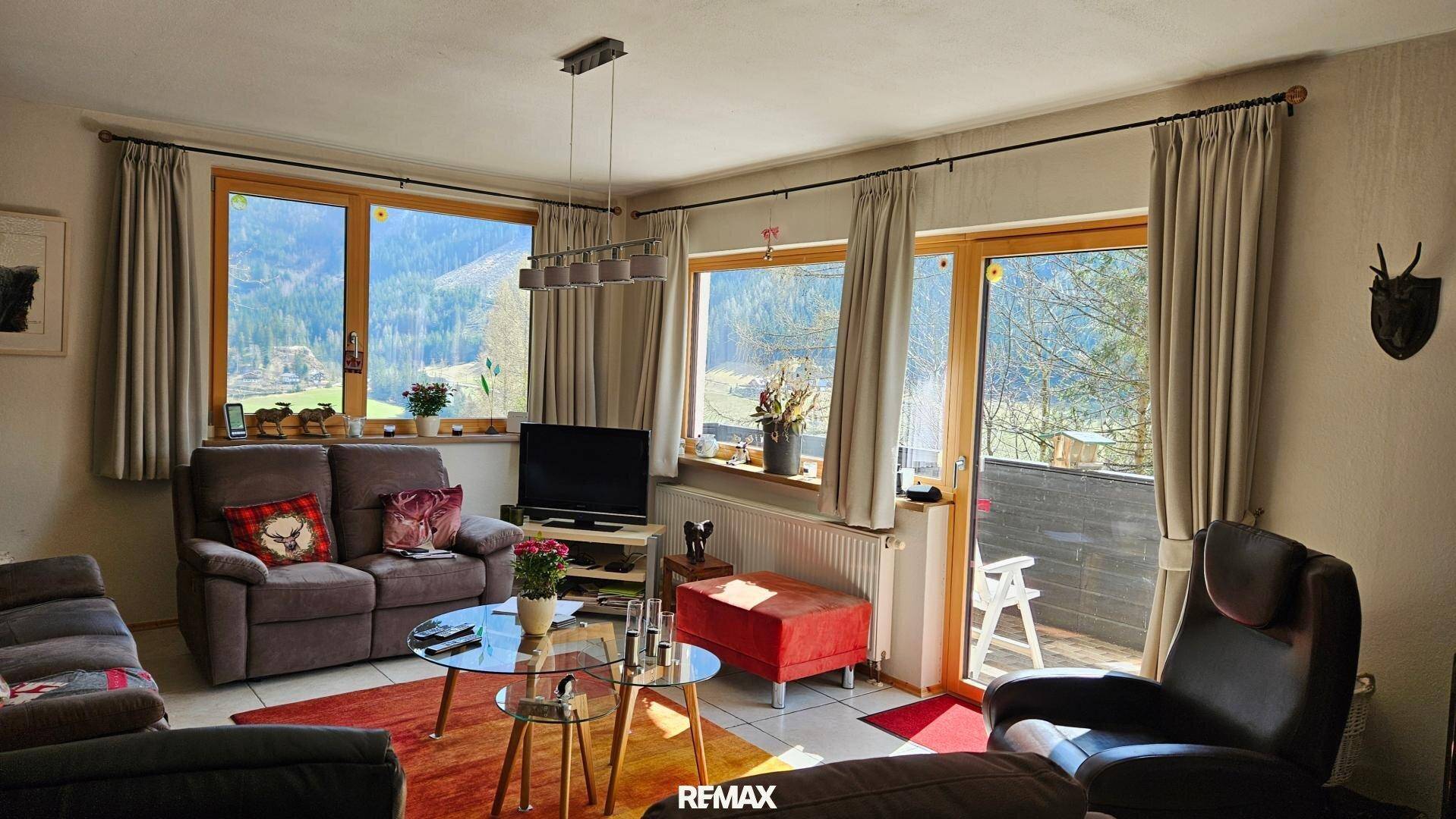 Helles Wohnzimmer mit Zugang zum Balkon und weitem Blick auf die umliegende Natur.