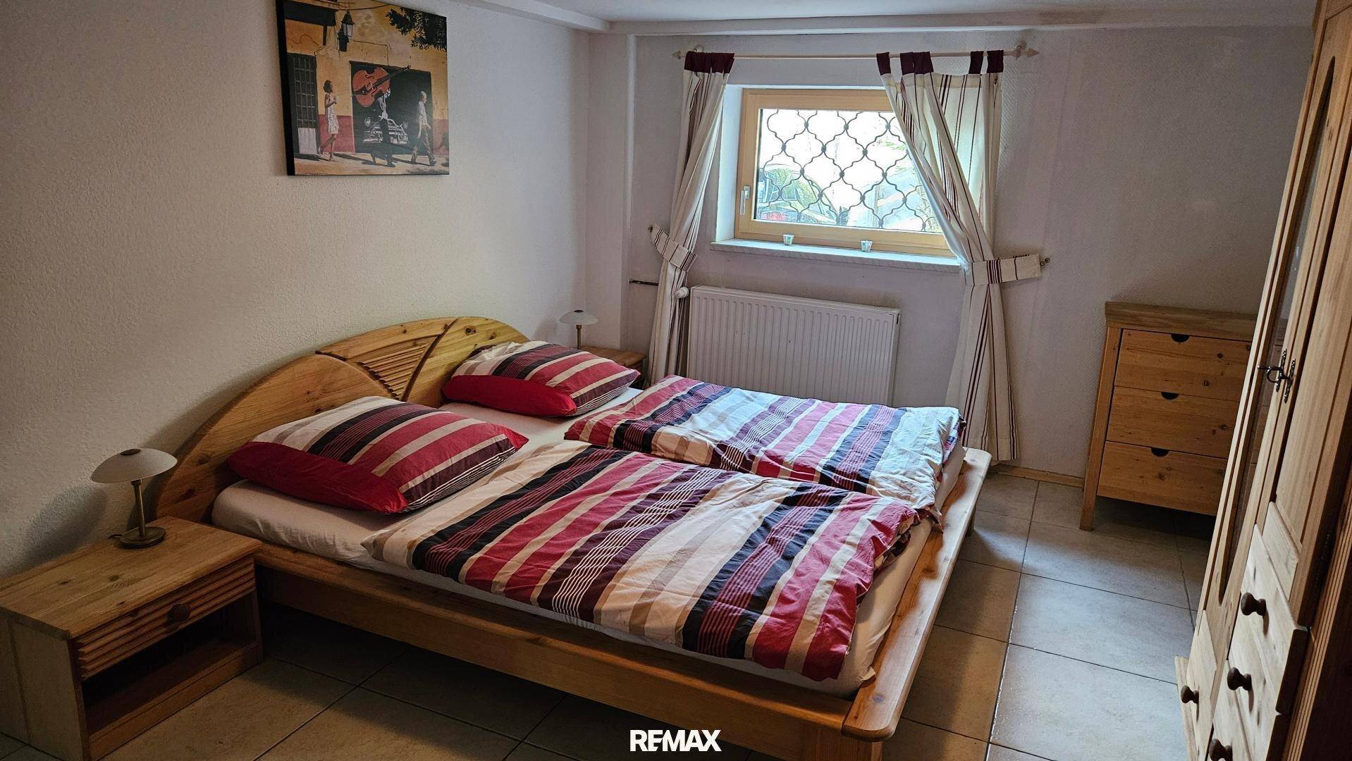 Helles Schlafzimmer mit traditionellem Doppelbett, Nachttischen und Kleiderschrank aus Holz.