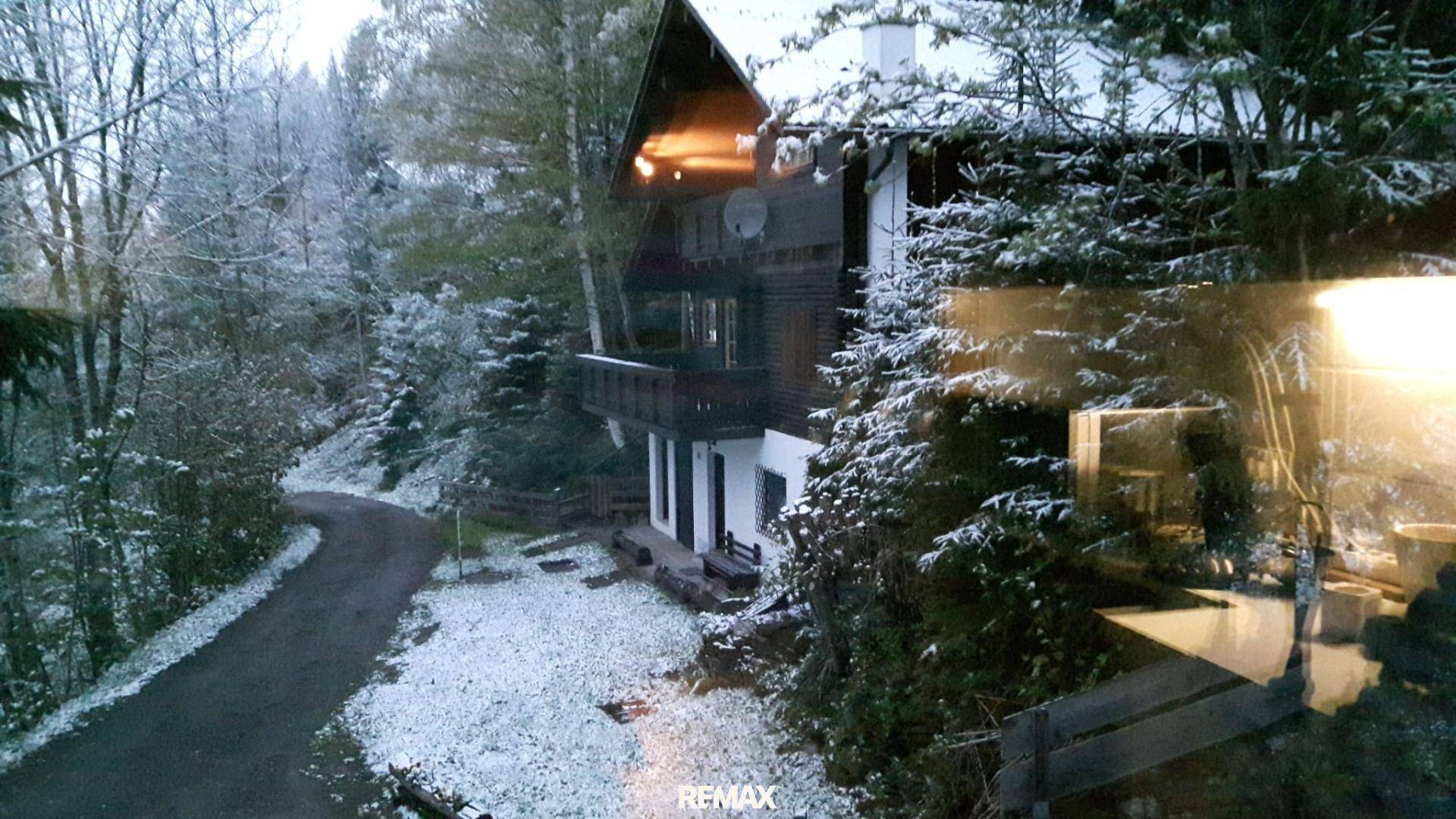Winterliche Ansicht des Hauses mit verschneiter Umgebung, gesehen durch eine Fensterscheibe.
