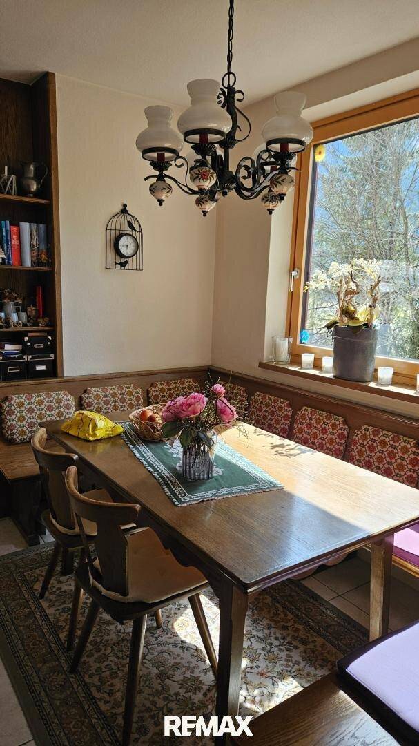 Traditioneller Essbereich mit Eckbank, Holztisch und einem Fenster mit Blick auf die Natur.