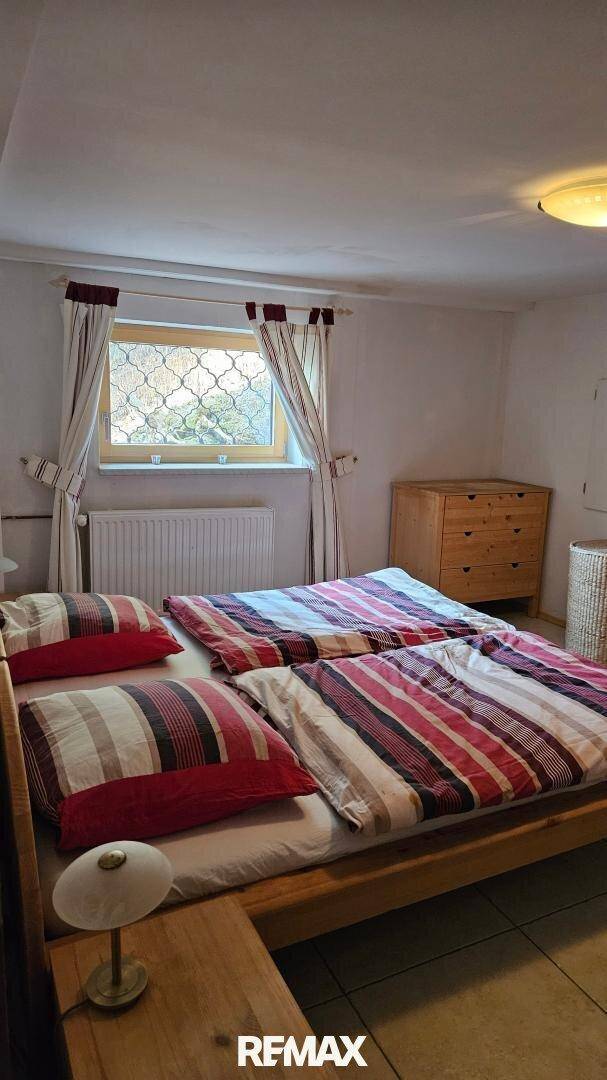 Gemütliches Schlafzimmer mit zwei Einzelbetten, Holzmöbeln und einem Fenster mit Gitter.
