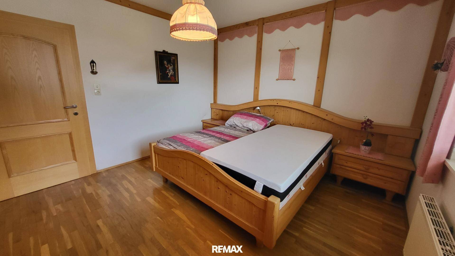 Gemütliches Schlafzimmer mit traditionellem Holzbett, passenden Nachttischen und Holzvertäfelung.