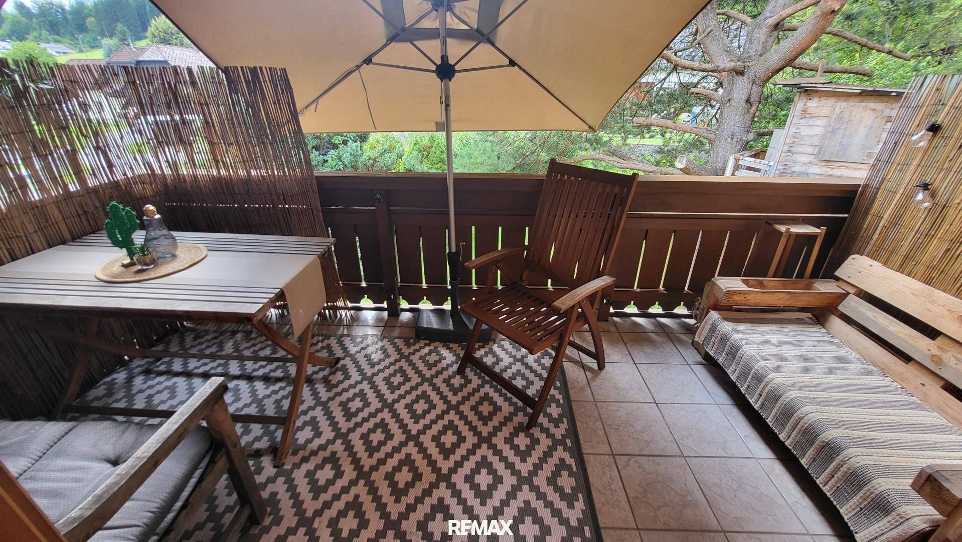 Gemütlicher Balkon mit Fliesenboden, Sonnenschirm und Sitzgelegenheiten für entspannte Stunden.