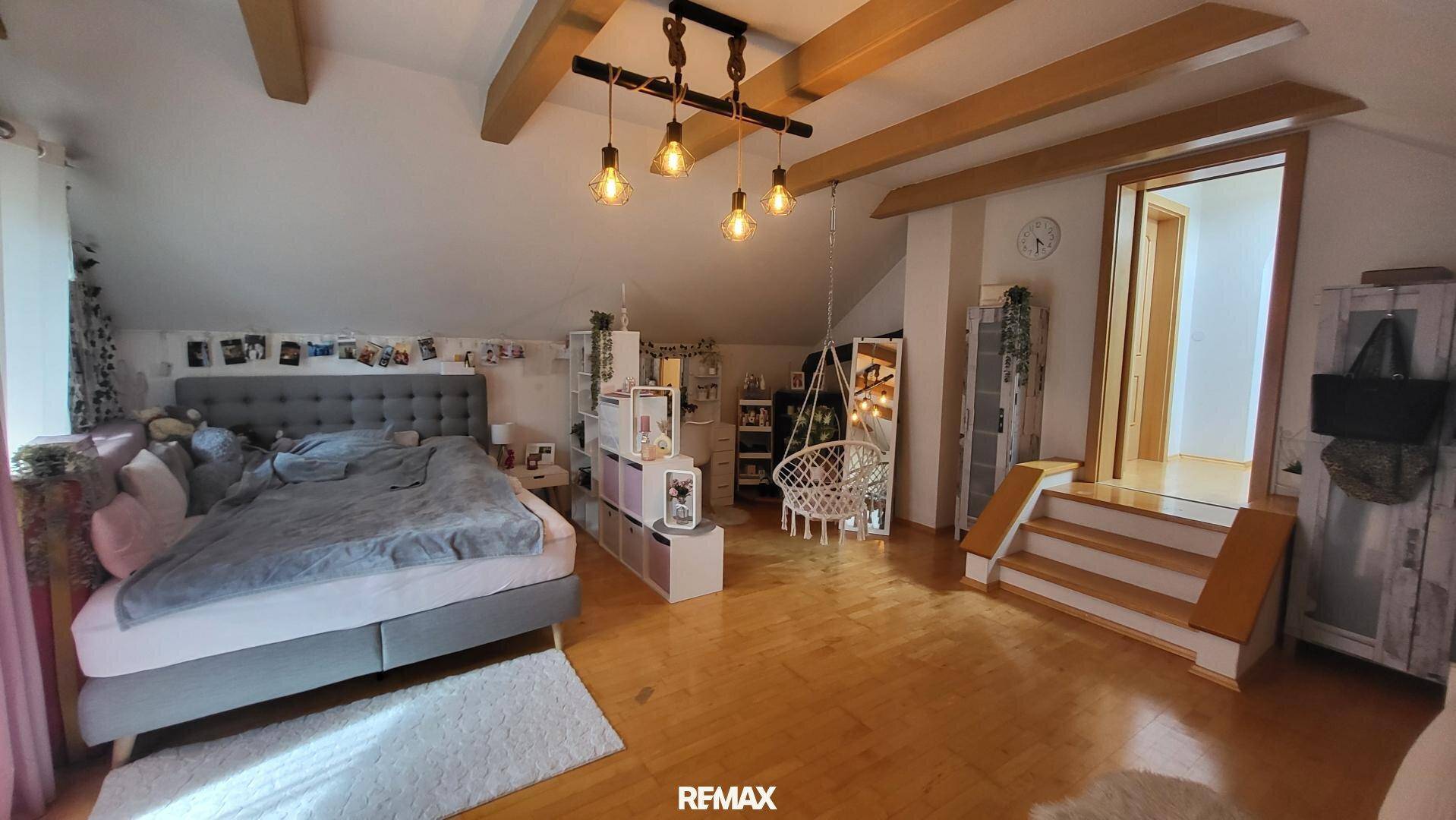 Geräumiges Schlafzimmer im Dachgeschoss mit Holzbalken, Doppelbett und viel Stauraum.