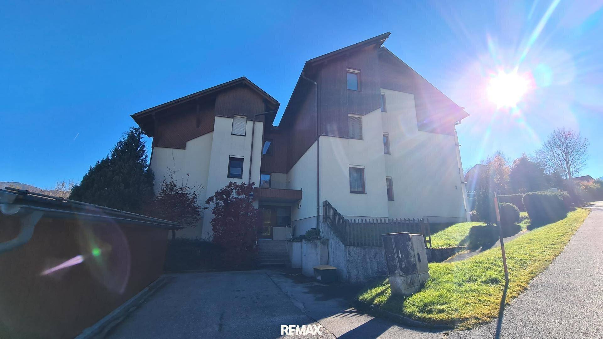 Rückansicht des Mehrfamilienhauses mit Zufahrt und sonniger Lage in der Natur.
