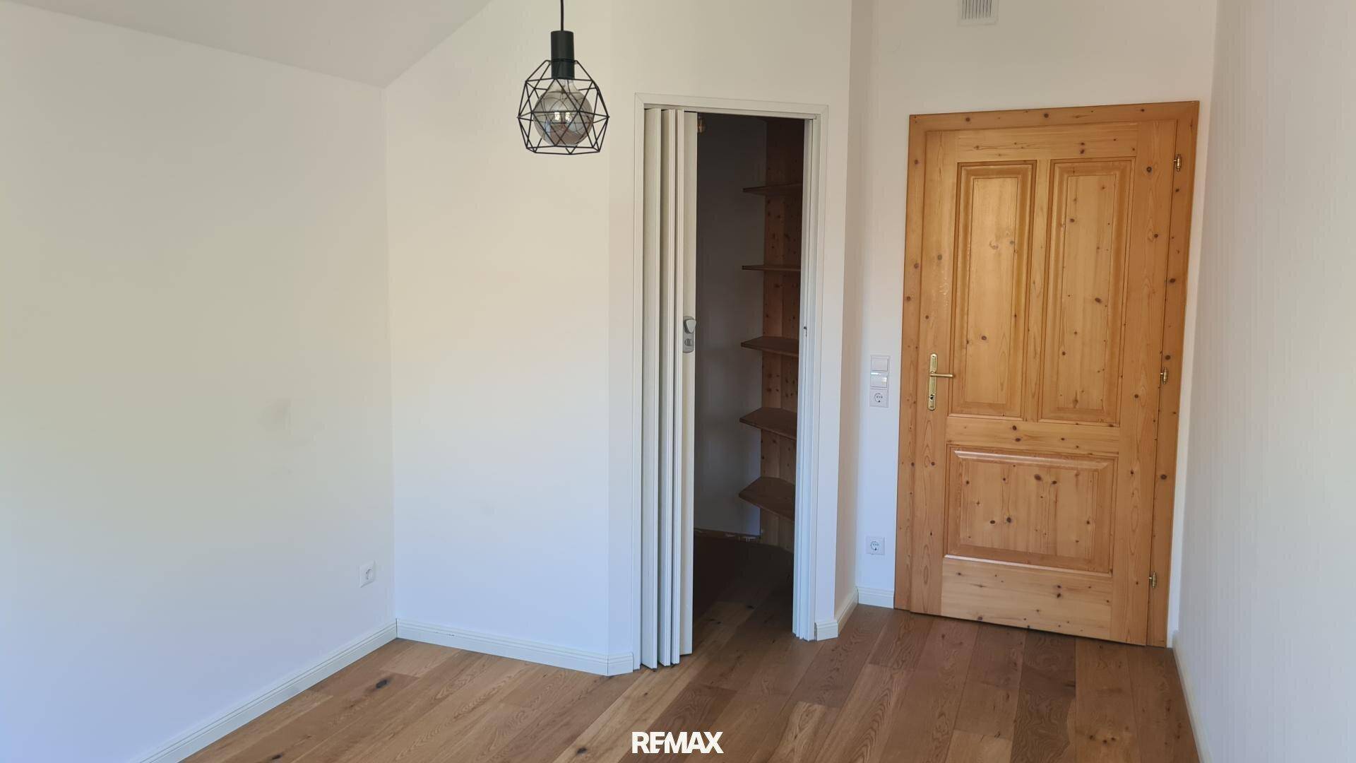 Schlafzimmer mit Holzboden, traditioneller Holztür und praktischem begehbarem Kleiderschrank.