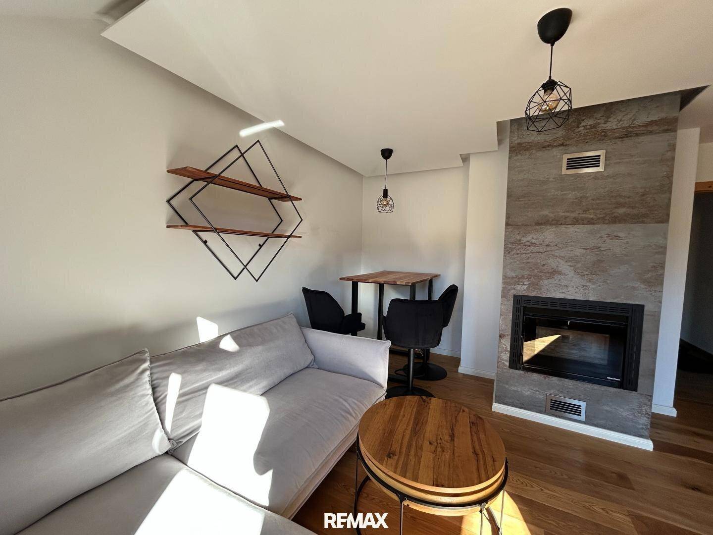 Offener Wohnbereich mit Kamin, Sofa und Essbereich, ideal für gesellige Abende.