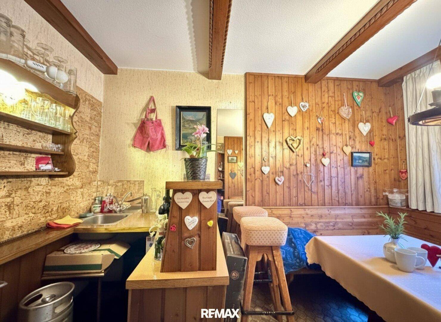 Gemütlicher Raum im alpinen Stil mit Holzvertäfelung, kleiner Bar und Sitzecke.