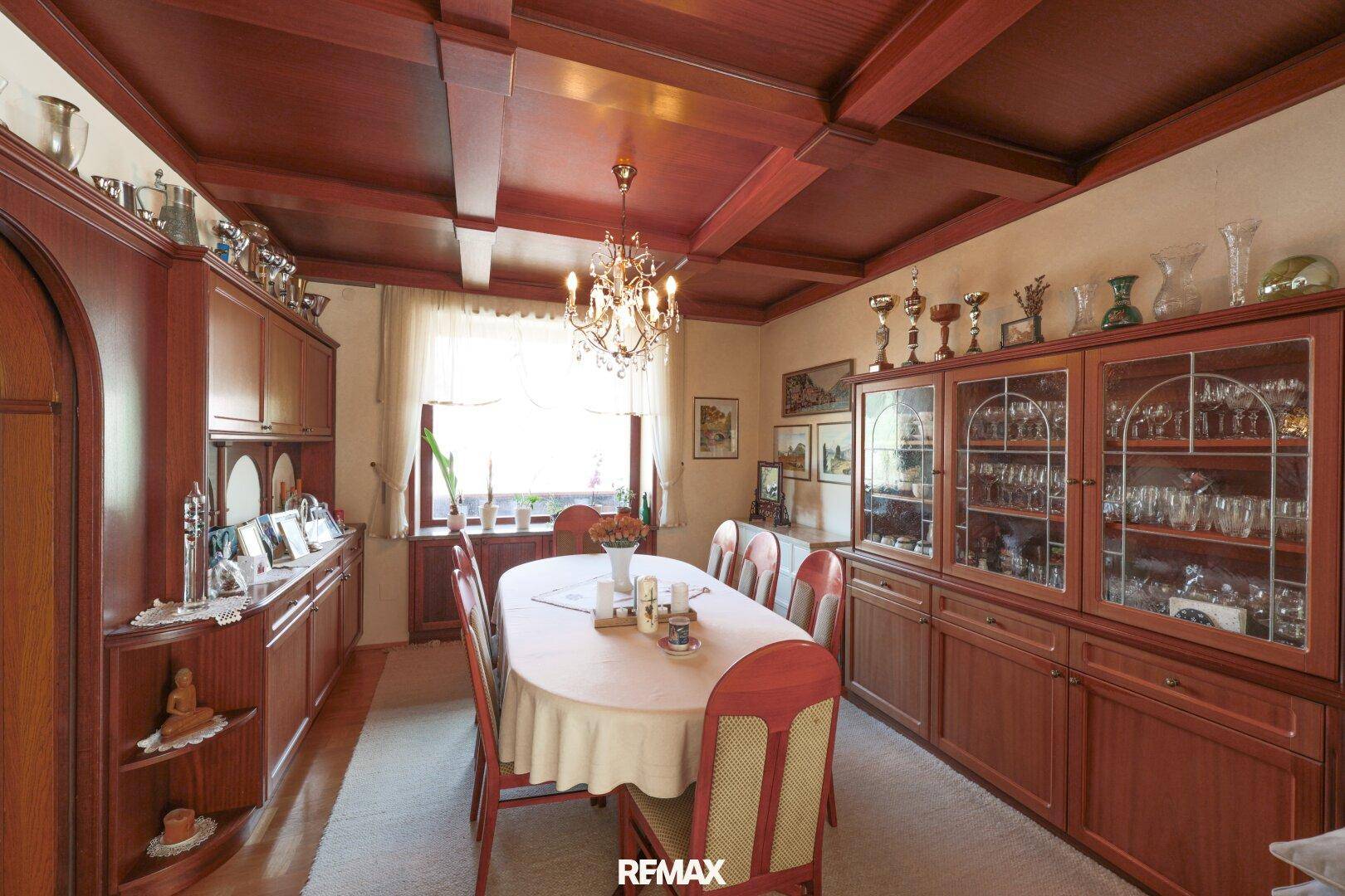 Klassisches Esszimmer mit großem Holztisch, Kronleuchter und Holzvertäfelung.