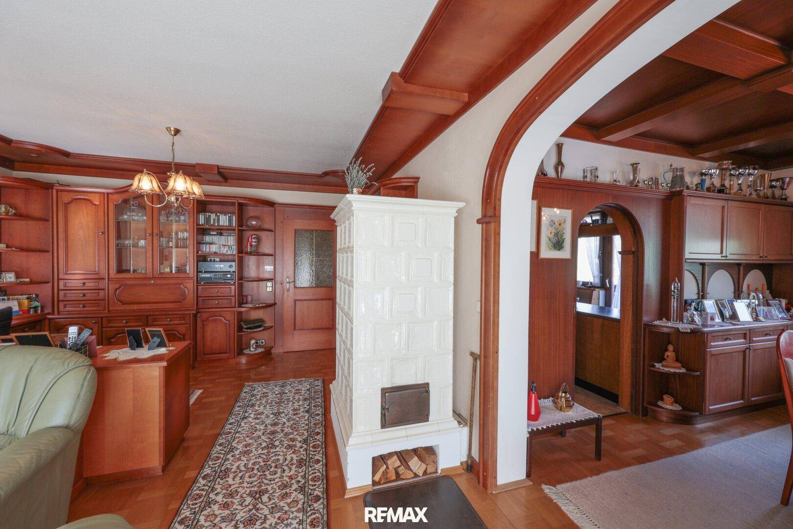Geräumiges Wohnzimmer mit Kachelofen, Holzvertäfelung und traditionellen Möbeln.