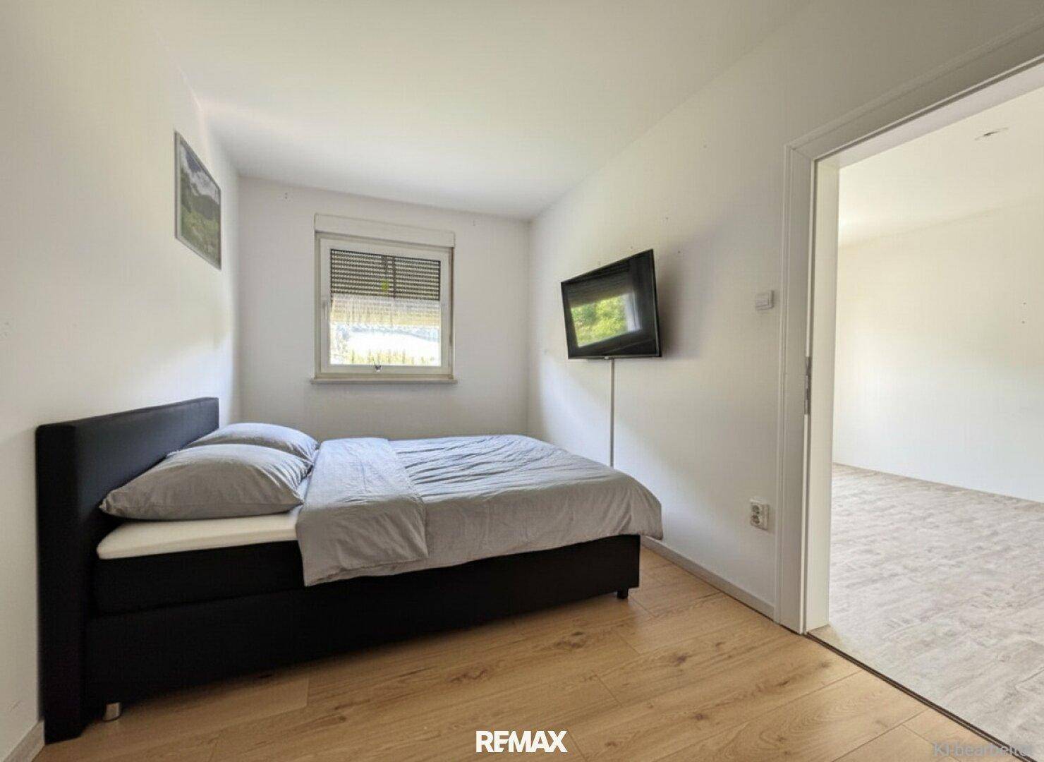 Kleines Schlafzimmer mit Einzelbett, Holzboden und Fenster mit Außenjalousie.