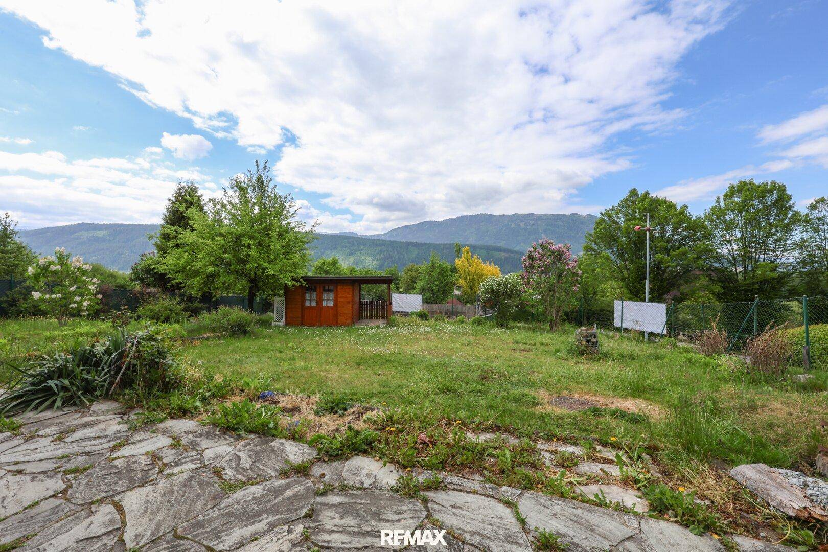 Großer Gartenbereich mit Holzschuppen und weitem Blick auf die umliegende Berglandschaft.