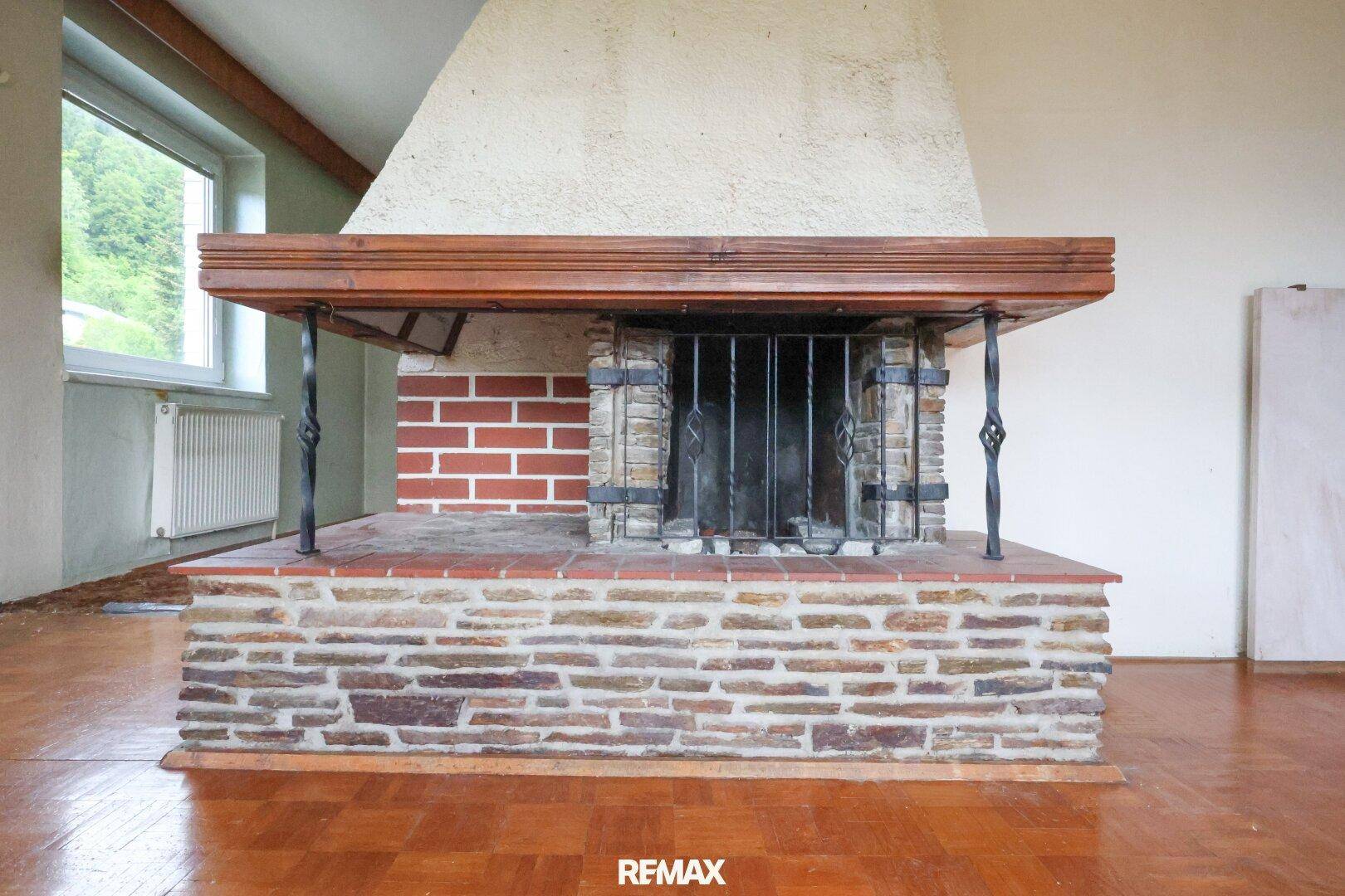 Geräumiges Wohnzimmer mit traditionellem Kamin und Parkettboden, bereit zur Renovierung.