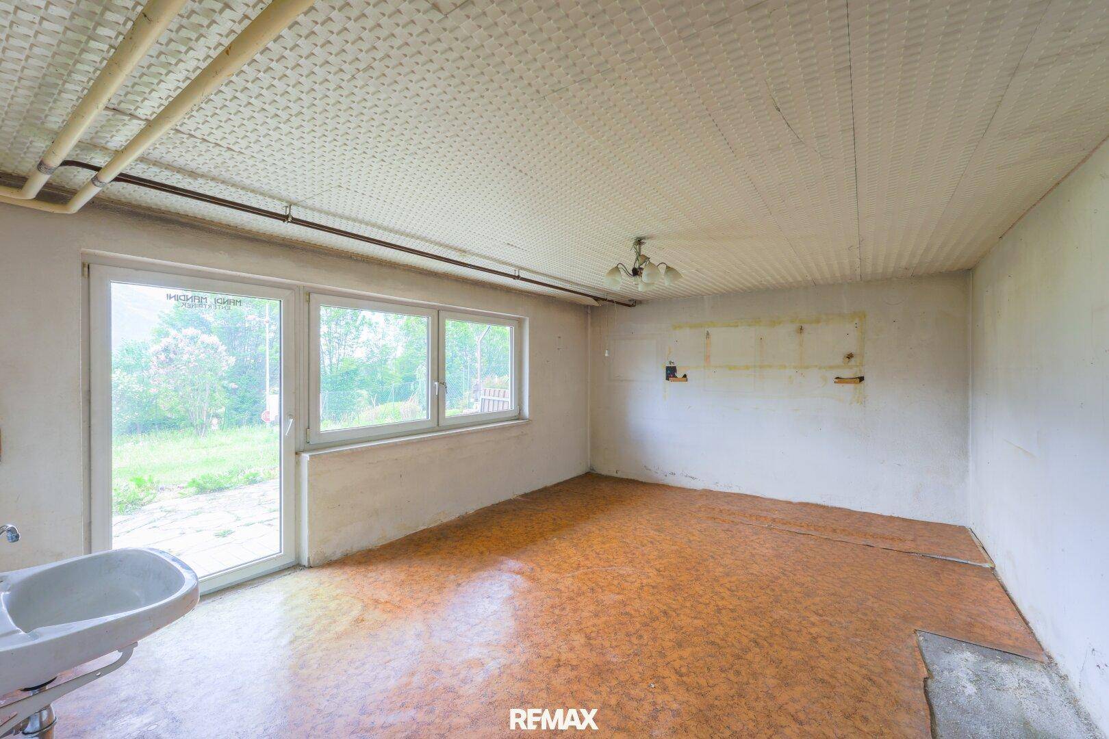 Raum mit Waschbecken, großen Fenstern und Zugang zum Außenbereich, ideal für Renovierungsprojekte.