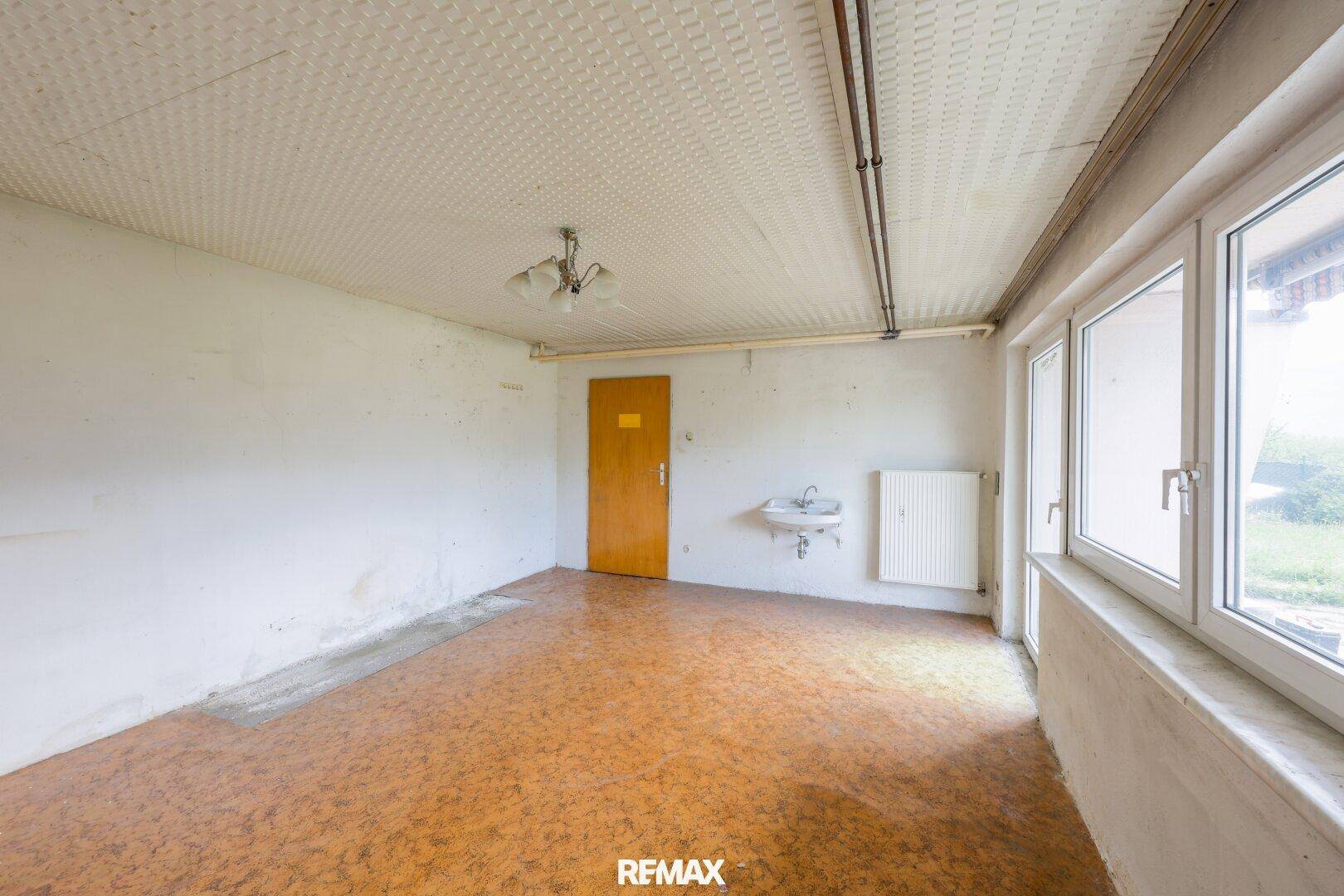 Heller Raum mit Fensterfront, Heizkörper und Waschbecken, bietet Potenzial zur Umgestaltung.