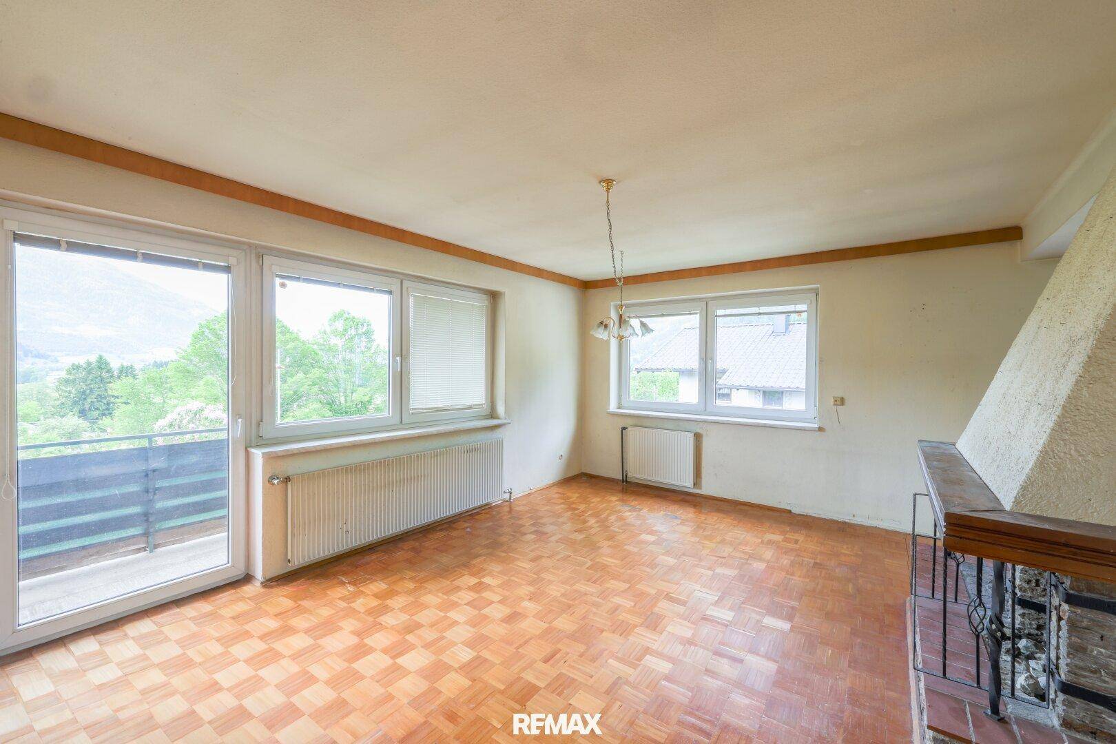Wohnzimmer mit Kamin, Parkettboden und Zugang zu einem Balkon mit schöner Aussicht.