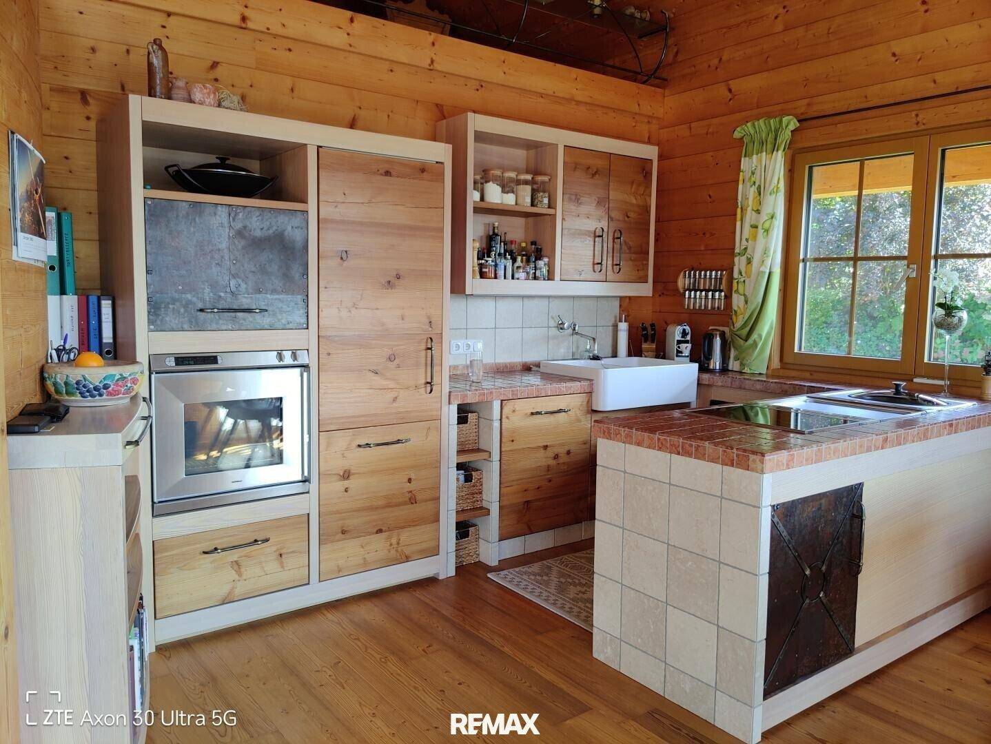 Rustikale Holzküche mit gefliesten Arbeitsplatten, integriertem Backofen und einem Fenster mit Blick ins Grüne.