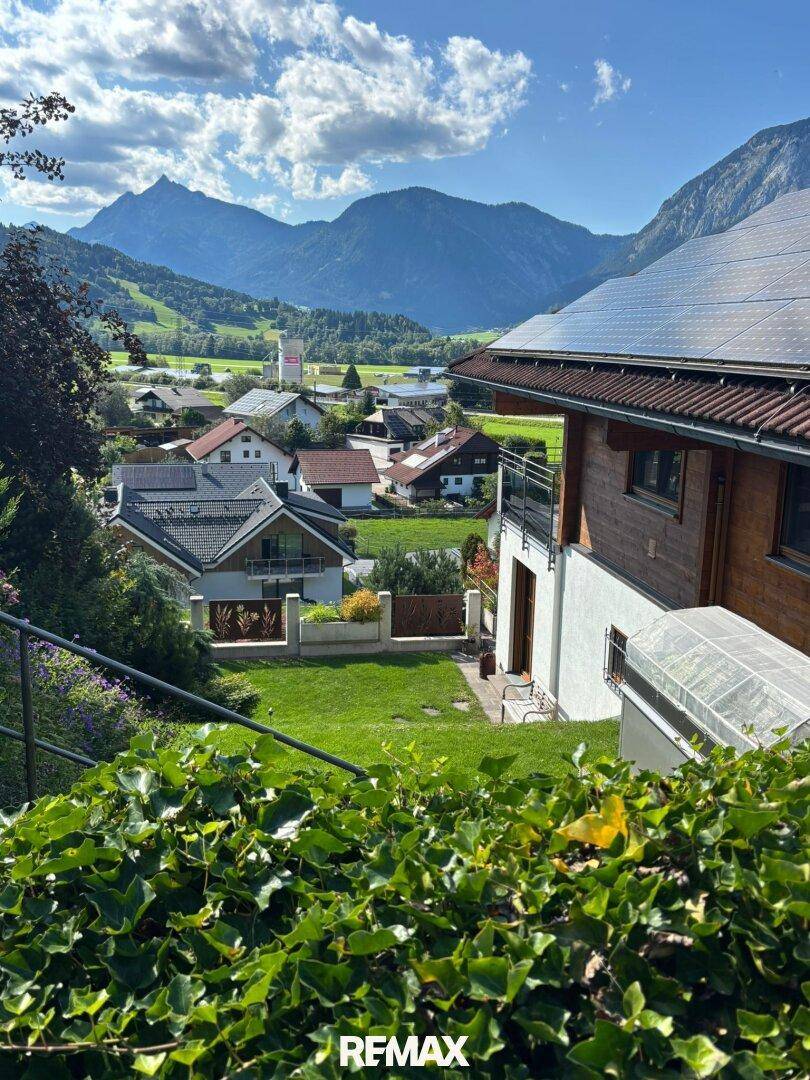 Seitenansicht des Hauses mit Solaranlage auf dem Dach und Blick auf die umliegende Nachbarschaft und Berge.
