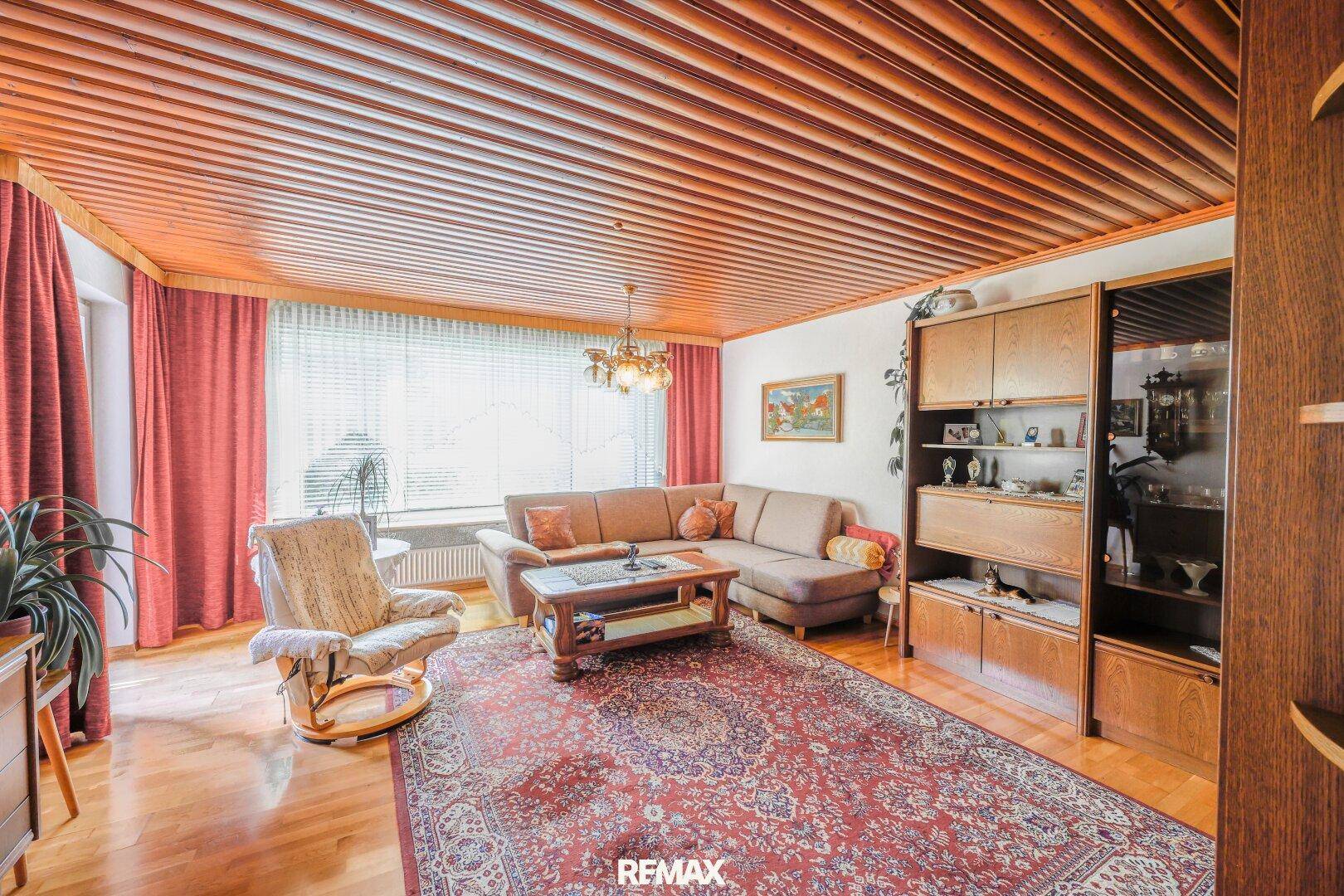 Gemütliches Wohnzimmer mit Holzdecke, traditionellem Teppich und bequemer Sitzecke.