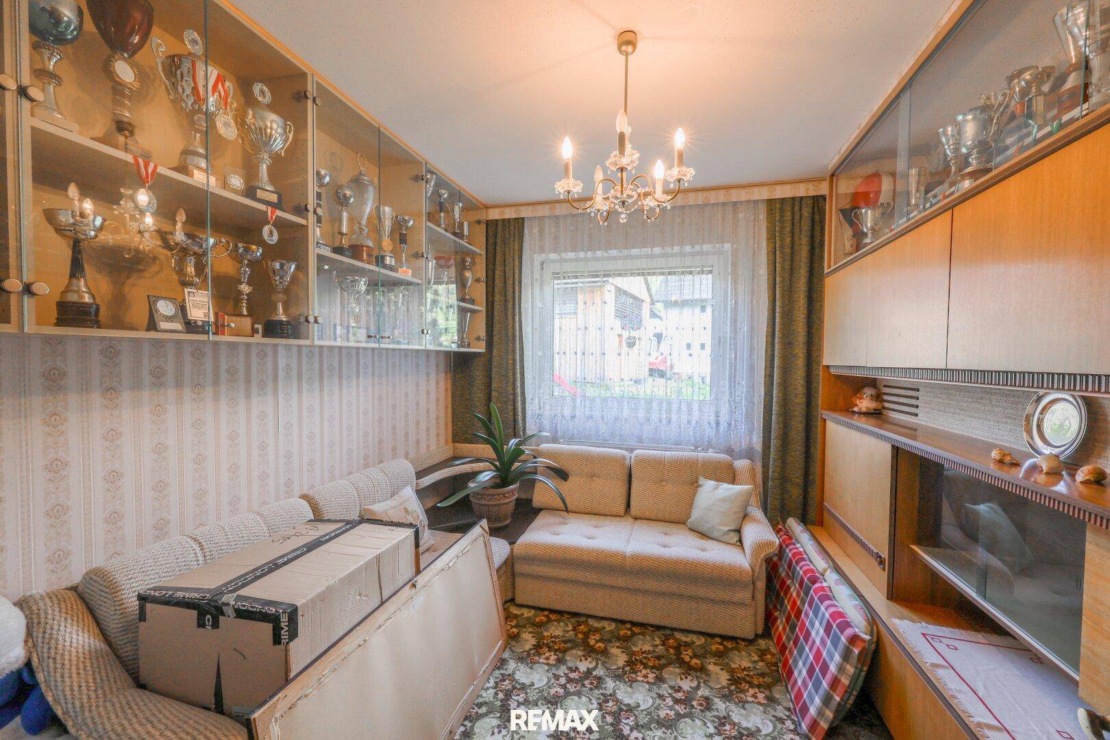 Weiterer Wohnraum mit Sofa, Vitrinen und gemusterter Tapete, ideal als Gästezimmer.