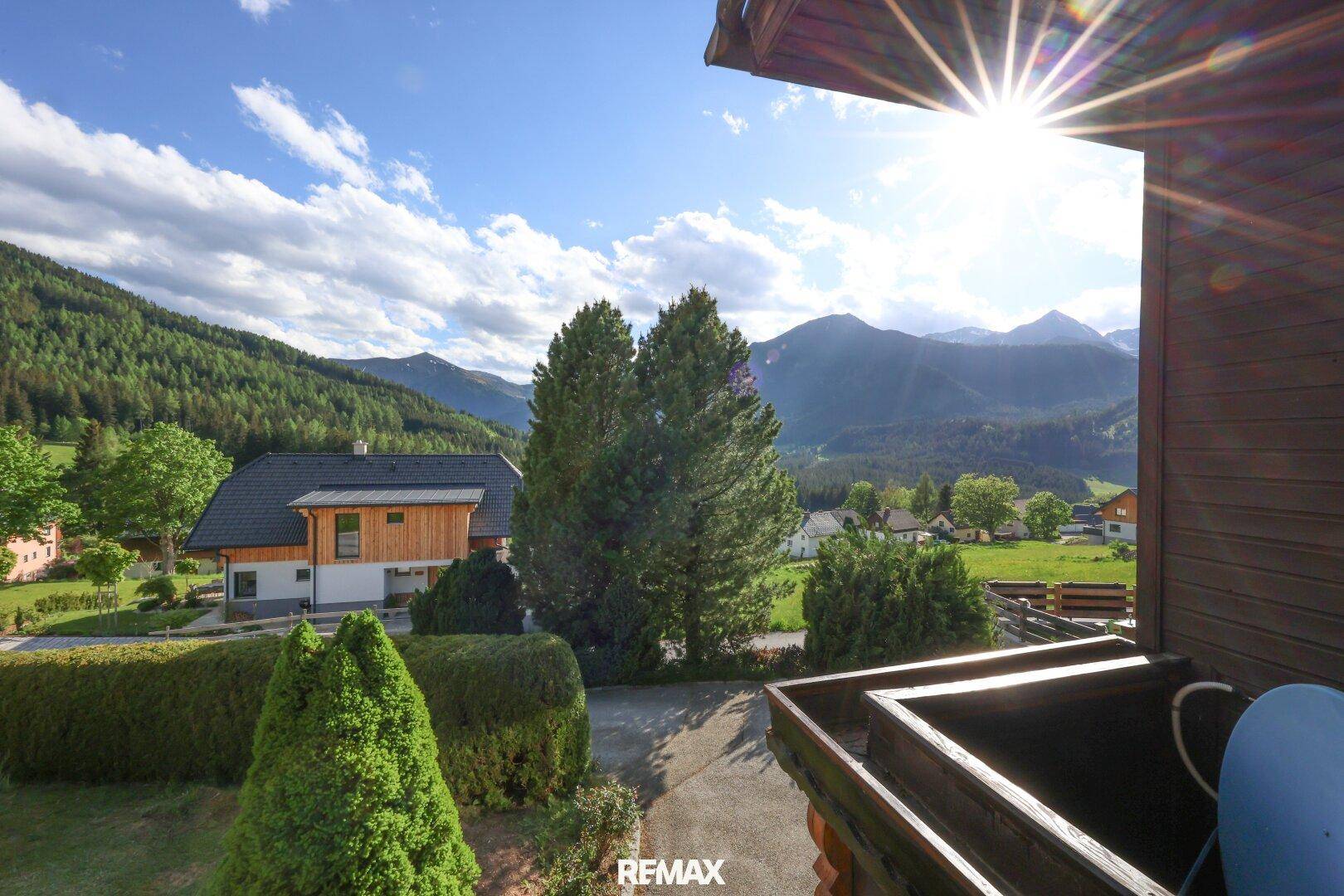 Sonniger Balkon mit atemberaubendem Blick auf die umliegende Berglandschaft und viel Grün.