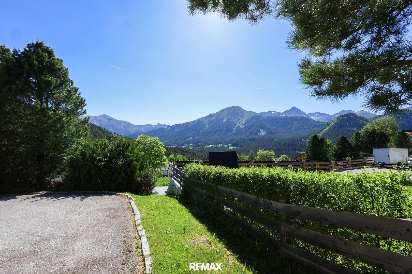 Panoramablick auf die majestätischen Berge und die umliegende grüne Natur unter blauem Himmel.