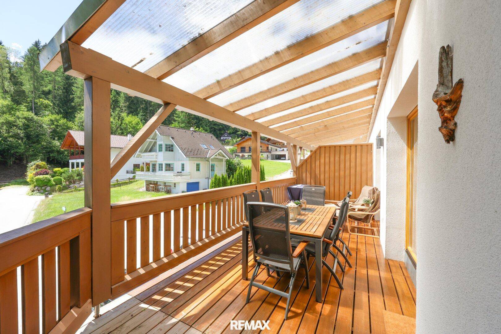 Sonniger Essbereich auf der Holzterrasse mit Blick auf die umliegende Berglandschaft.