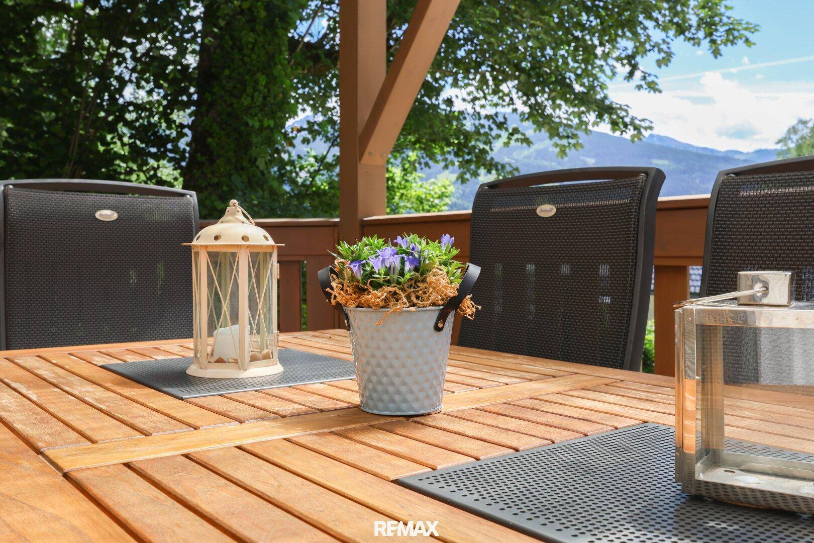 Nahaufnahme des dekorierten Esstisches auf der Holzterrasse, bereit für Mahlzeiten im Freien.