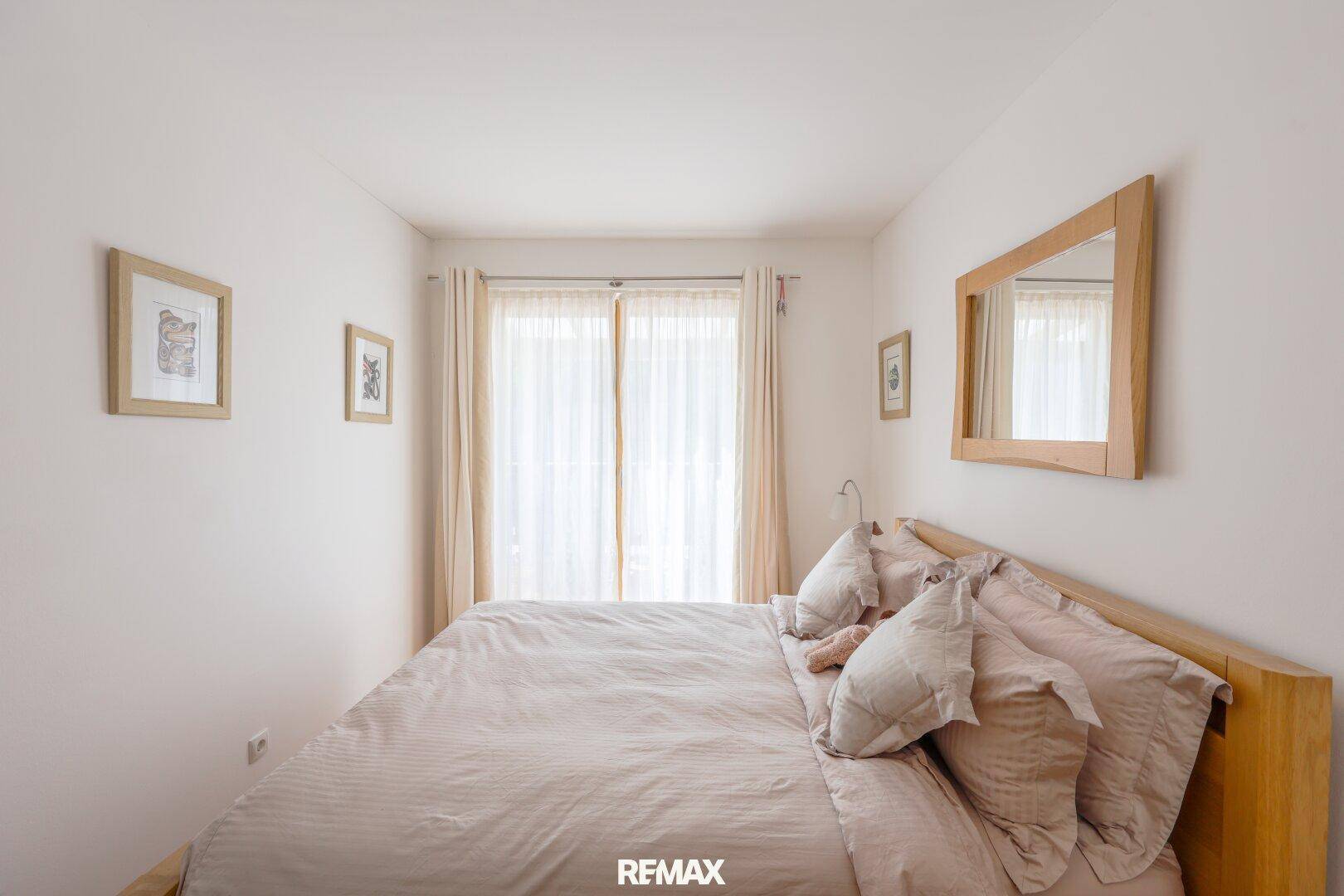 Gemütliches Schlafzimmer mit hellem Holzdoppelbett und einem großen Fenster für viel Tageslicht.