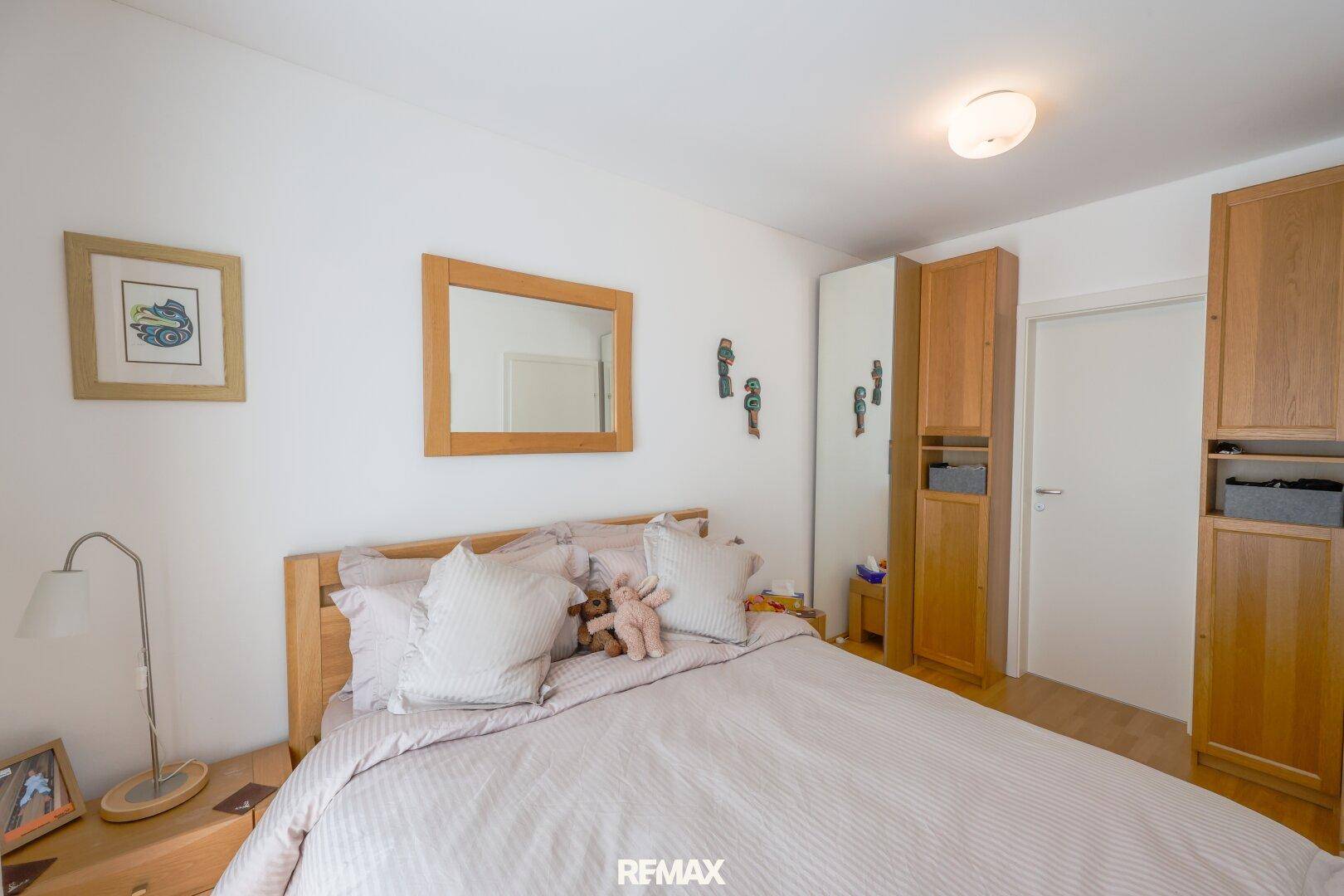 Schlafzimmer mit Doppelbett, Holzschrank und einem Spiegel, der den Raum optisch vergrößert.