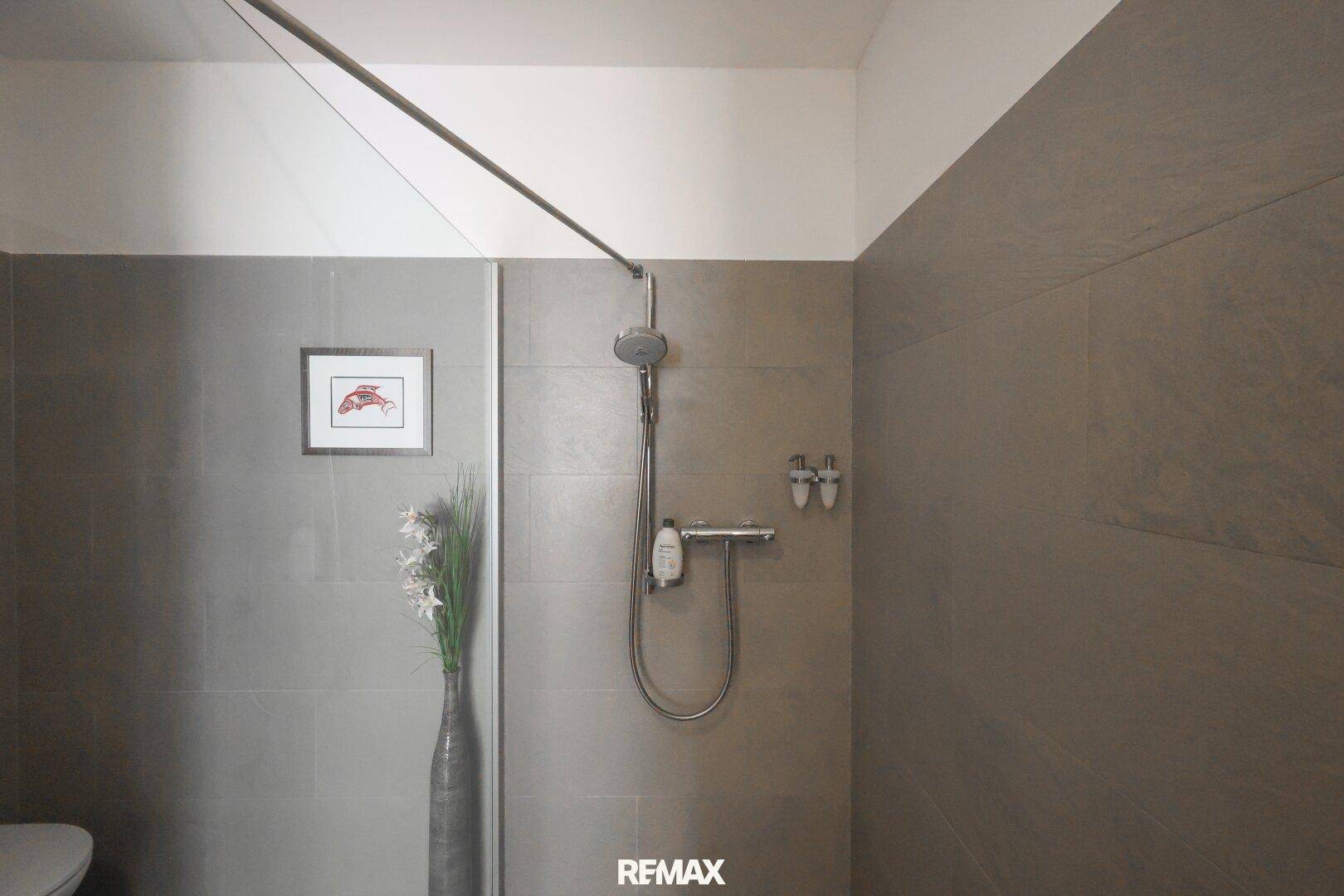 Geräumige begehbare Dusche mit Glaswand und modernen Armaturen im Badezimmer.