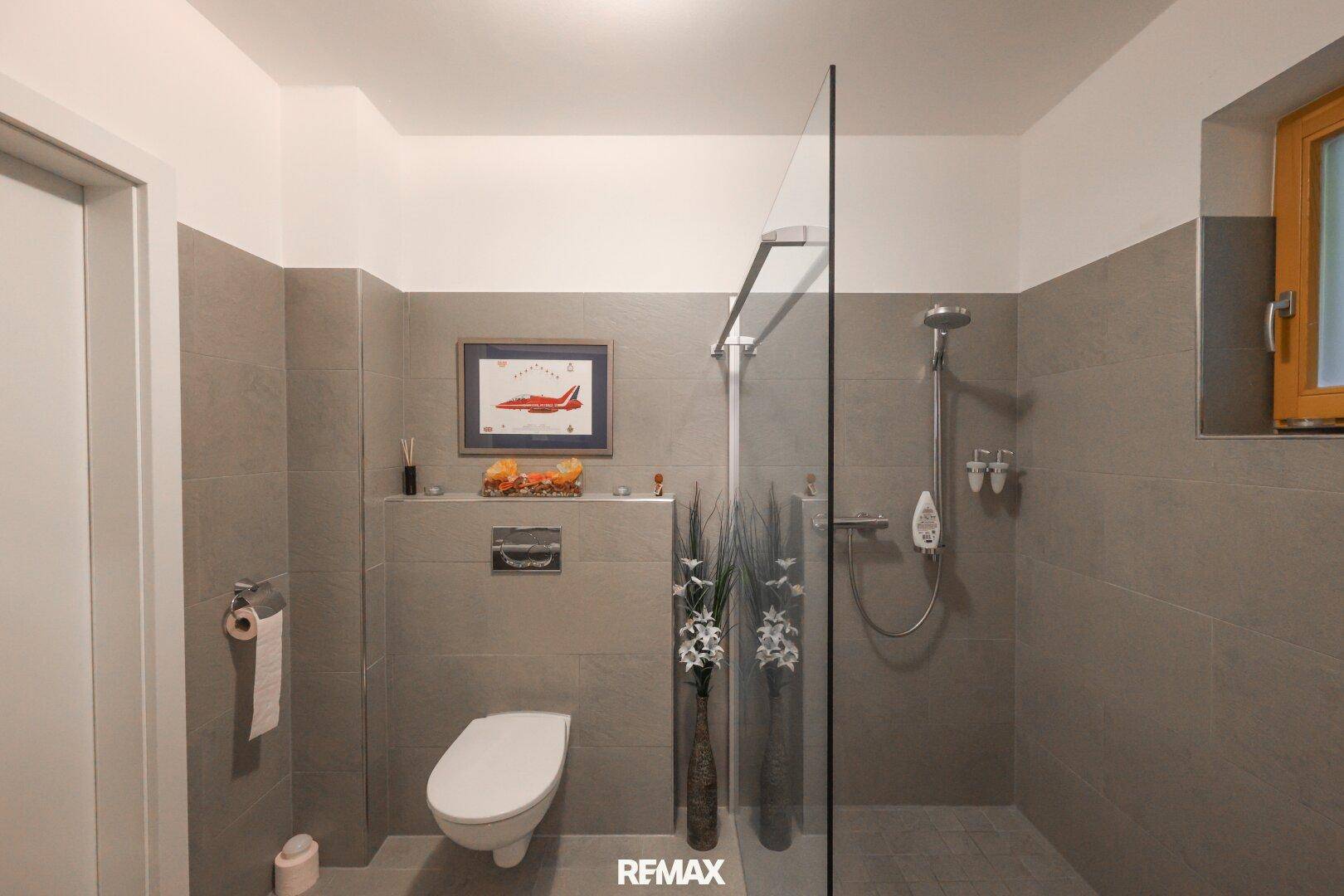 Funktionales Badezimmer mit wandhängender Toilette und geräumiger begehbarer Dusche.